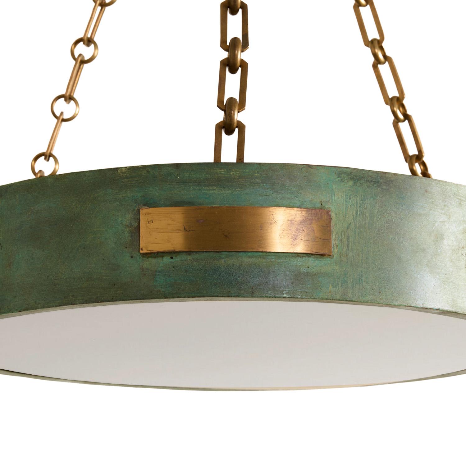 A round, single-tiered pendant light with a verdigris finish and patinated brass horizontal panels on the dish and canopy. The dish suspended by three links of brass chain, and having an opal plexi diffuser, concealing 4 medium sockets. Can be