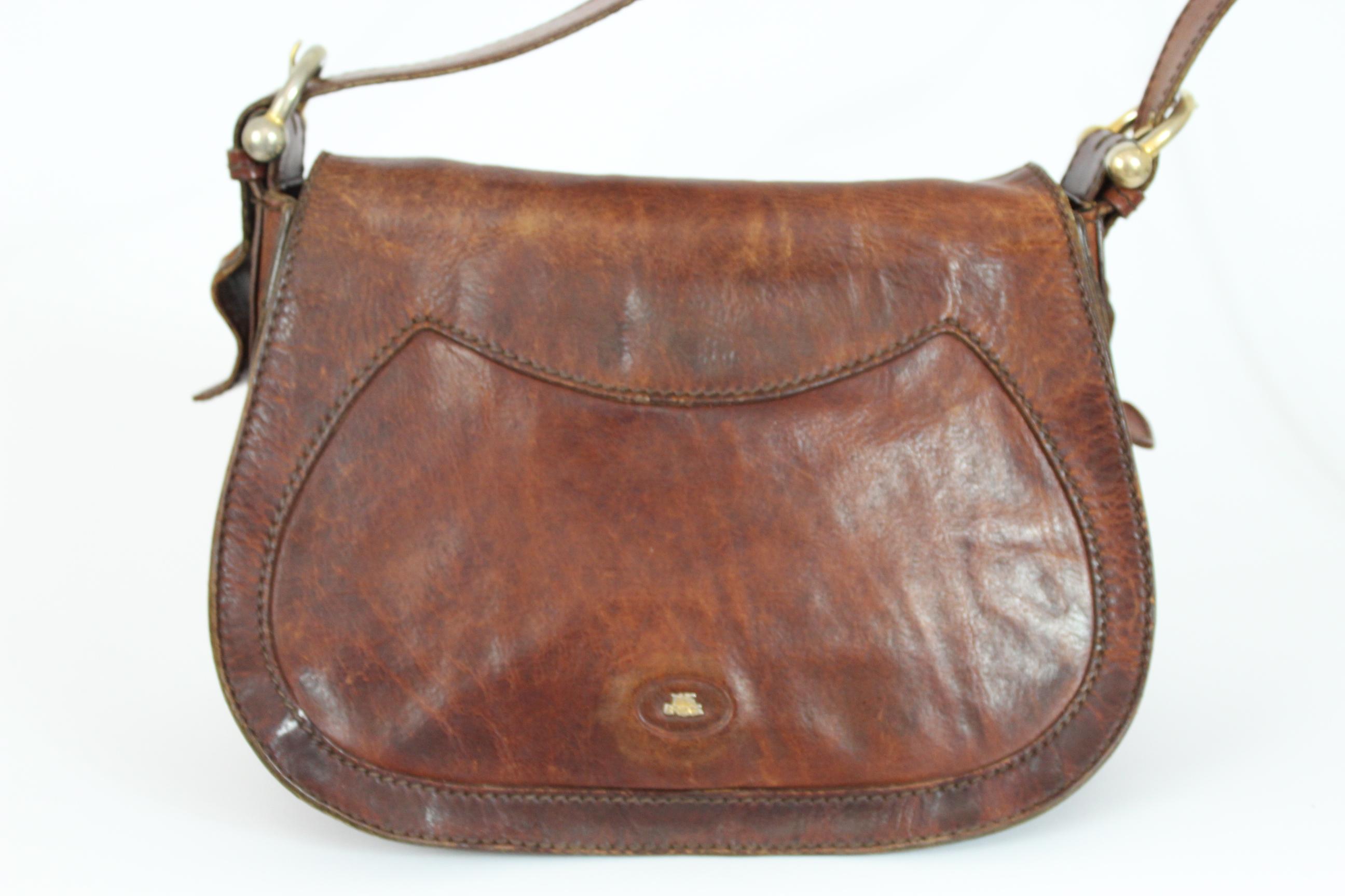 The Bridge vintage shoulder bag saddle model. Brown leather with adjustable shoulder strap. Front opening with magnetic clip, large zip pocket behind. Golden metallic details. Very spacious, logoed interior with zip pocket and cell phone