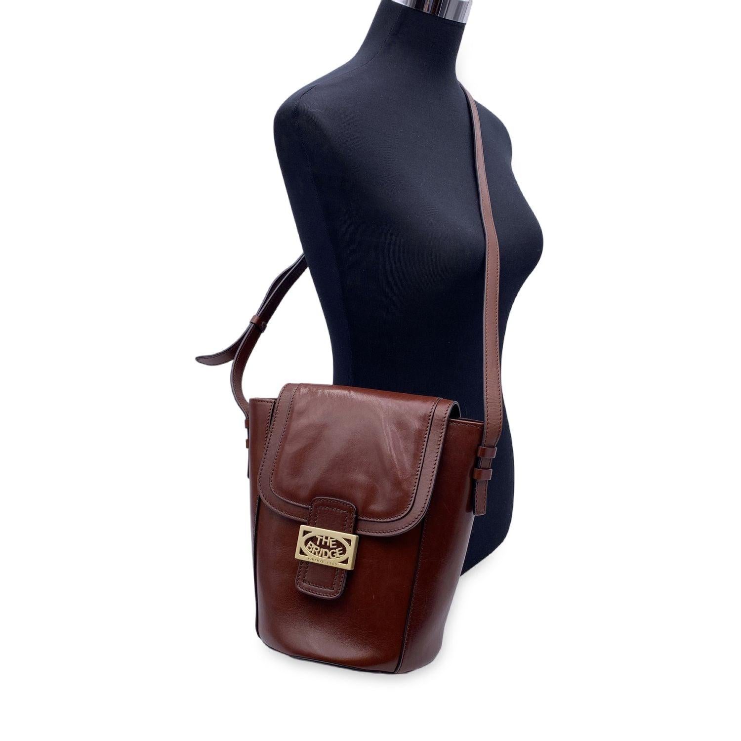 Vintage the Bridge bucket bag crafted in brown leather. Flap with magnetic button closure. Brown fabric lining. 1 zip pocket nside. Gold metal The Bridge logo on the front. Adjustable shoulder strap. The Bridge tag inside Condition A - EXCELLENT