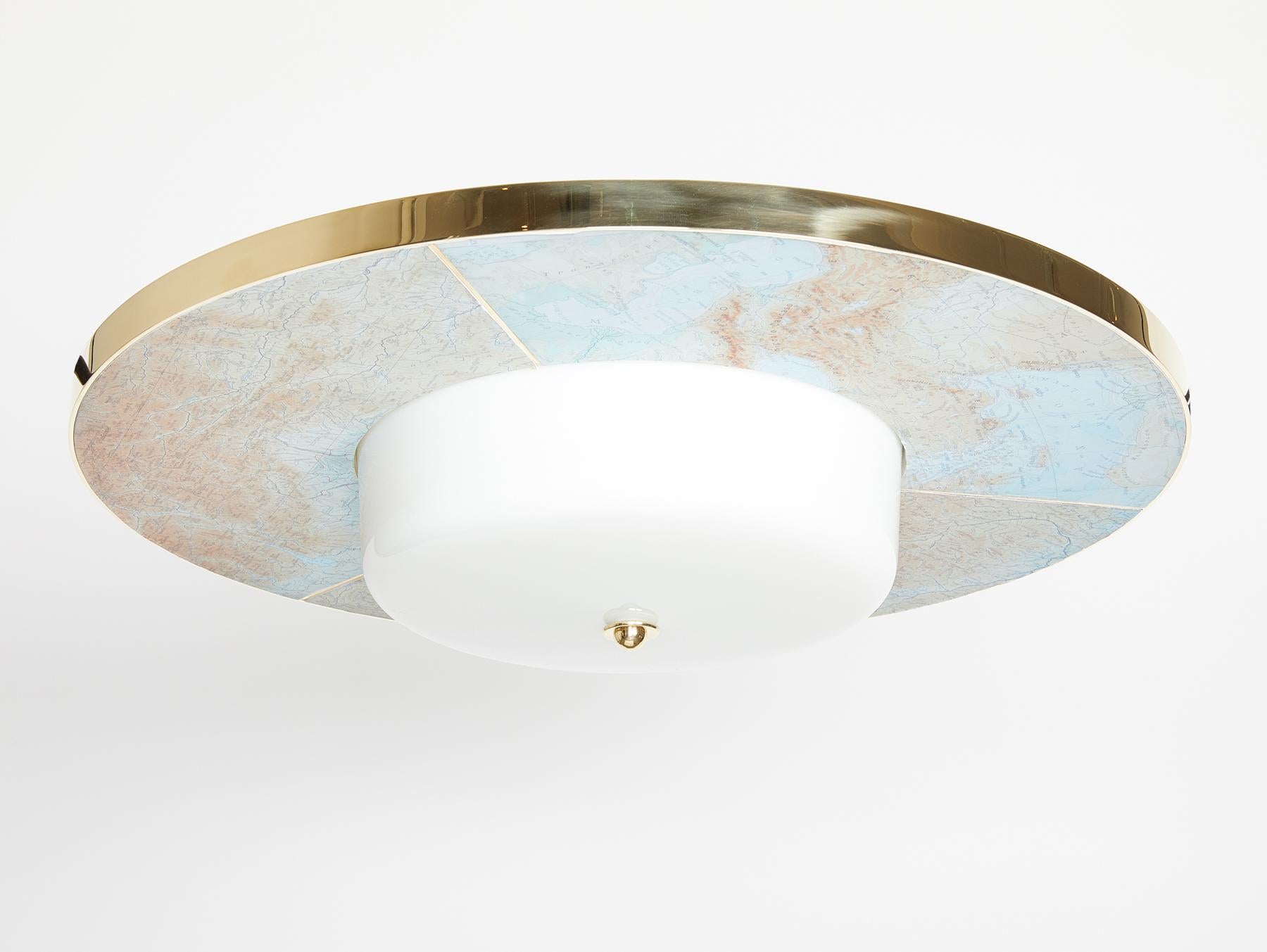 A flushmounted light fixture inspired by the Swedish Grace period, featuring a world map design, polished brass details, and white glass shade. This light is custom design by David Duncan LTD and can be made in various finishes and sizes.