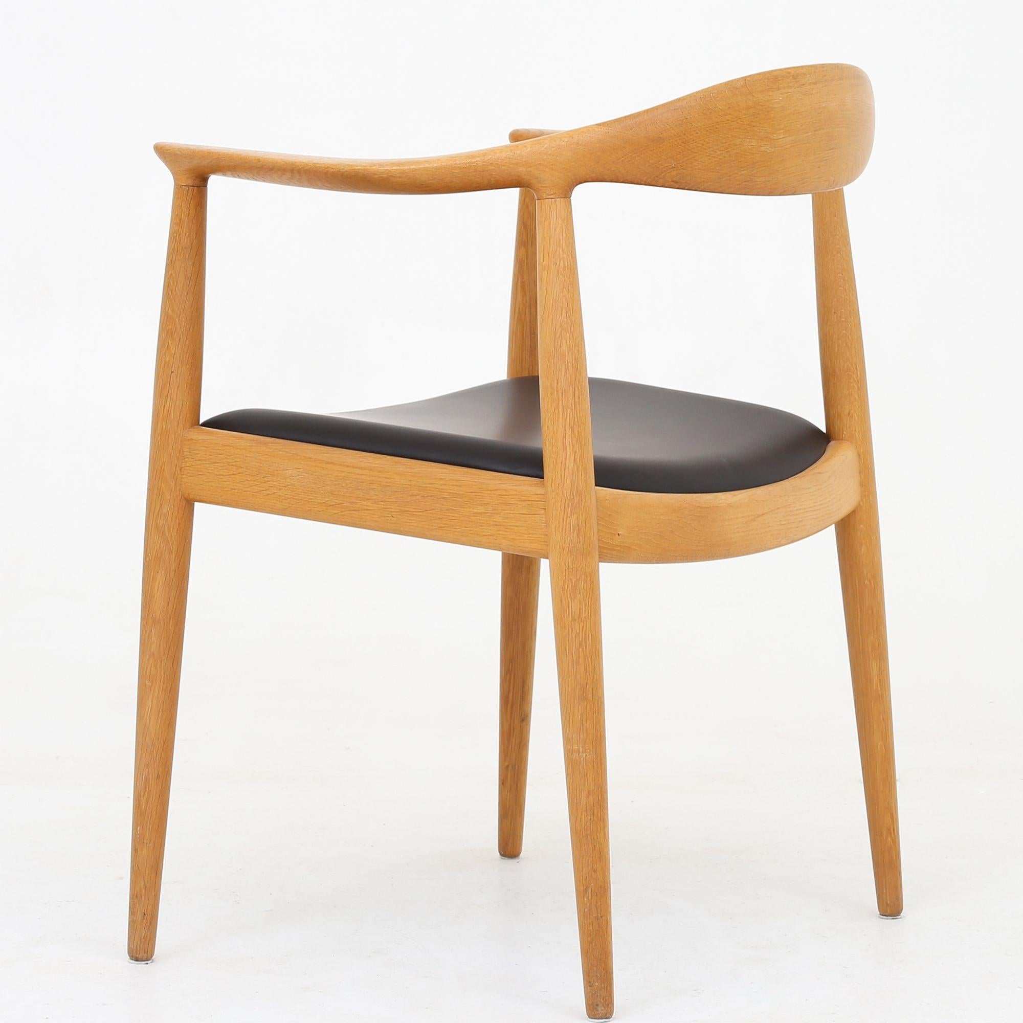 JH 503 - 'The Chair' in lacquered oak with dark brown leather seat. Hans J. Wegner / Johannes Hansen.
