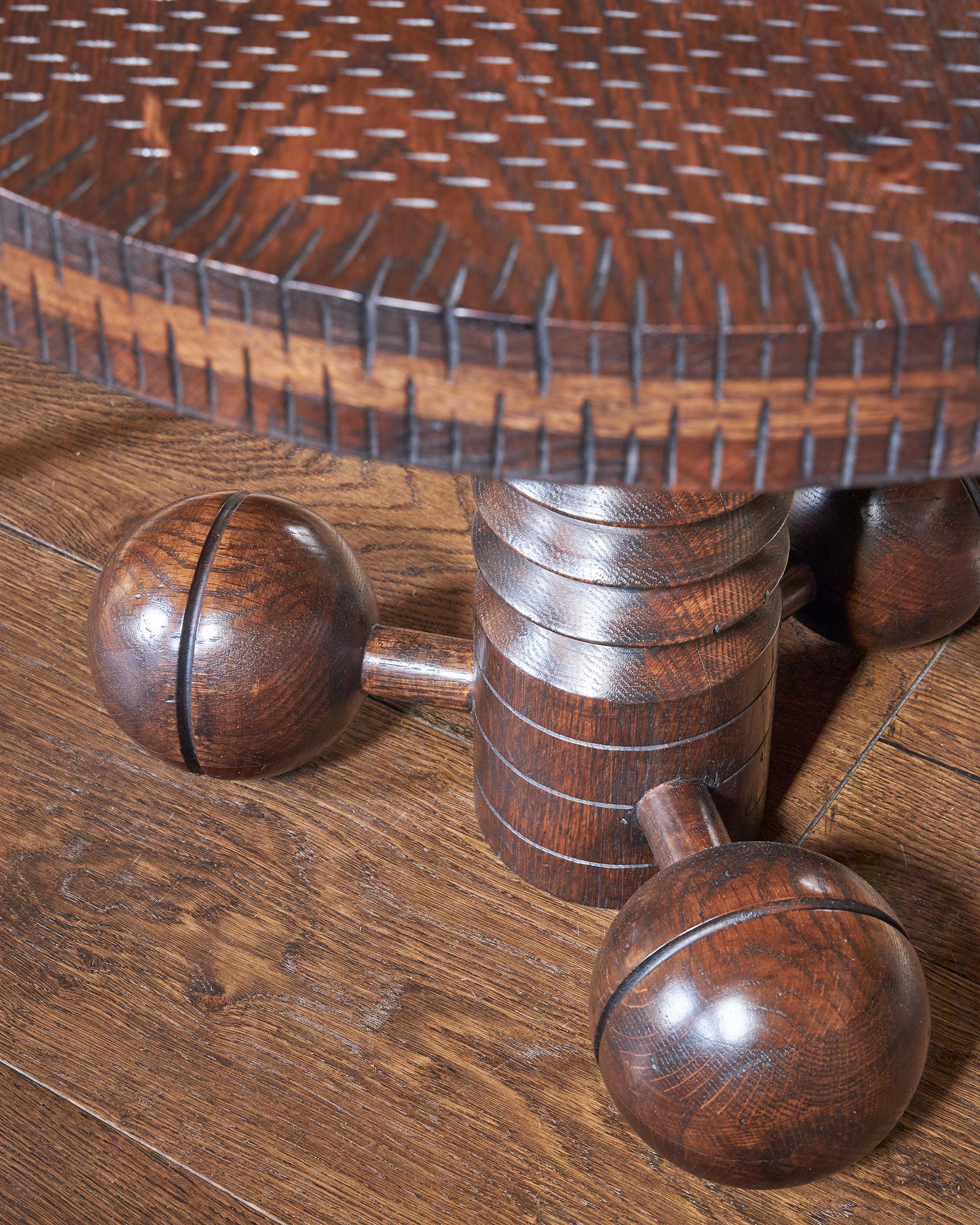 Petite table circulaire en chêne sculpté et tourné à la manière de Charles Dudouyt. Le plateau en chêne incisé repose sur une colonne en forme de tire-bouchon et sur trois pieds en forme de boule. Chêne poli légèrement vieilli. Finition sur mesure