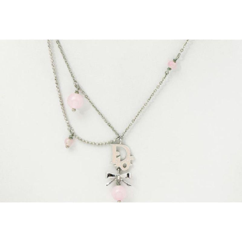 Ce collier Christian Dior est confectionné en métal argenté, avec un pendentif au logo Dior accompagné d'un nœud et de perles roses. Complété par une fermeture à pinces de homard.
 

57582MSC