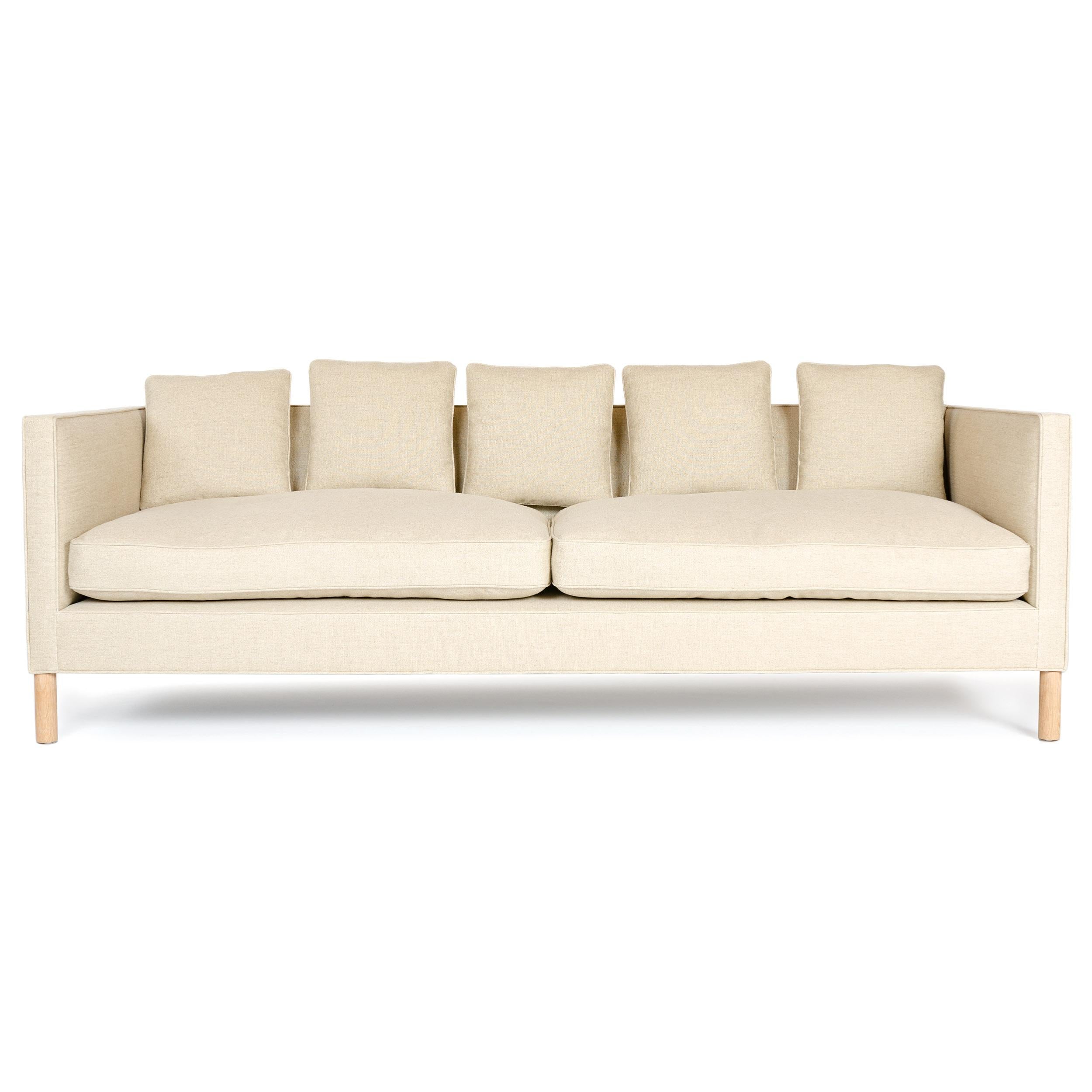 A minimal tuxedo sofa with solid wood frame and hand tied springs having down-filled cushions and pillow backs upholstered in natural linen.
 