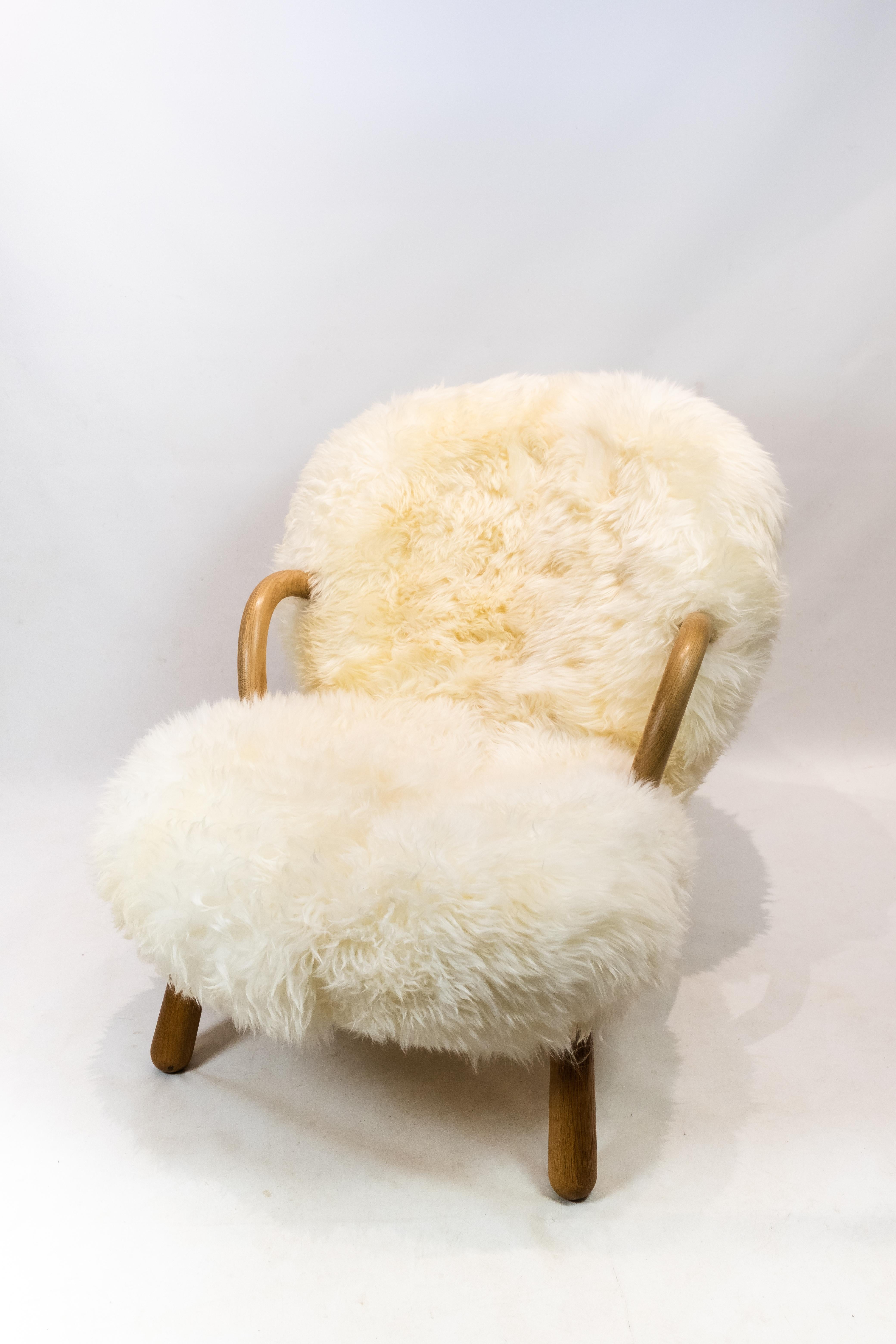 The clam chair originally designed by Phillip Arctander in 1944 and manufactured by Paustian. The chair is upholstered in sheep skin and with arms and legs of oak.