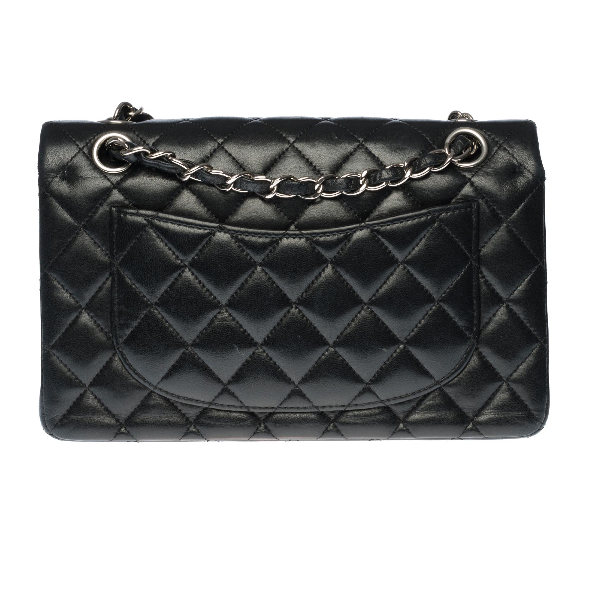 The coveted Chanel Timeless 23cm double flap bag in quilted black lambskin leather, silver metal hardware, silver metal chain intertwined with black leather for a shoulder and shoulder strap
Pocket on the back of the bag.
Closure with flap, silver
