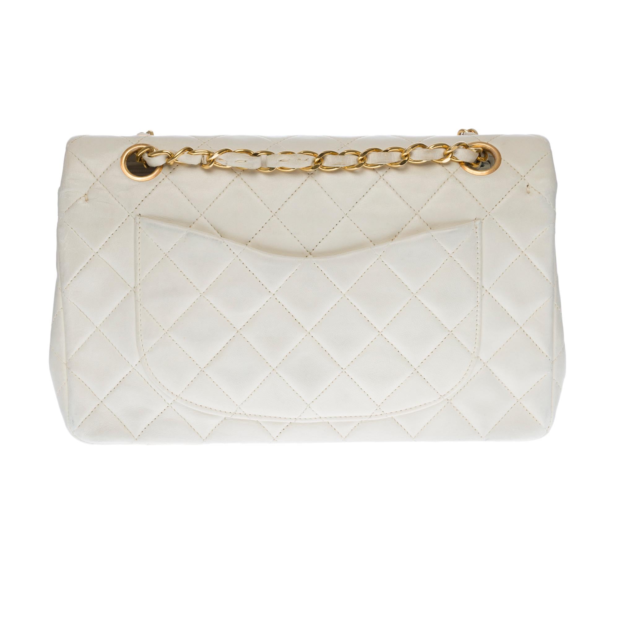 Beautiful Chanel Timeless Medium 23cm handbag with double flap in white quilted lambskin leather, gold metal hardware, a golden metal chain handle intertwined with white leather allowing a hand or shoulder support.
Closure with gold metal