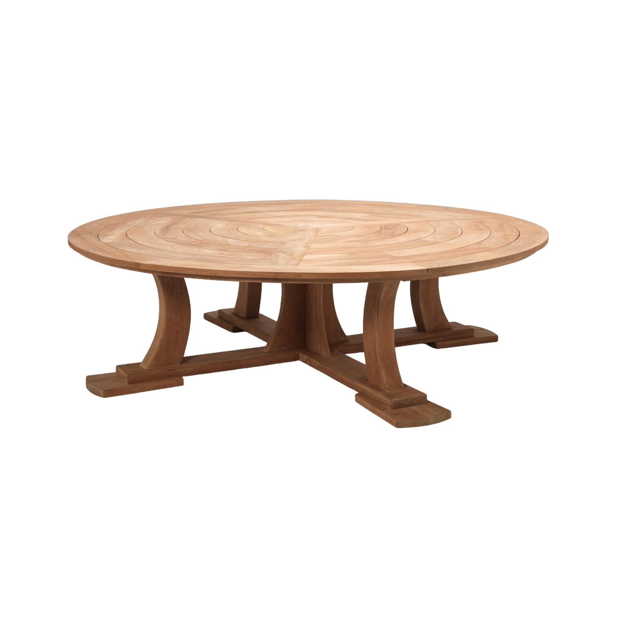 A fine country house circular teak garden table with six accompanying curved wood benches. The table seats 12 comfortably. The geometric design planked top above swept legs and quadriform platform base.