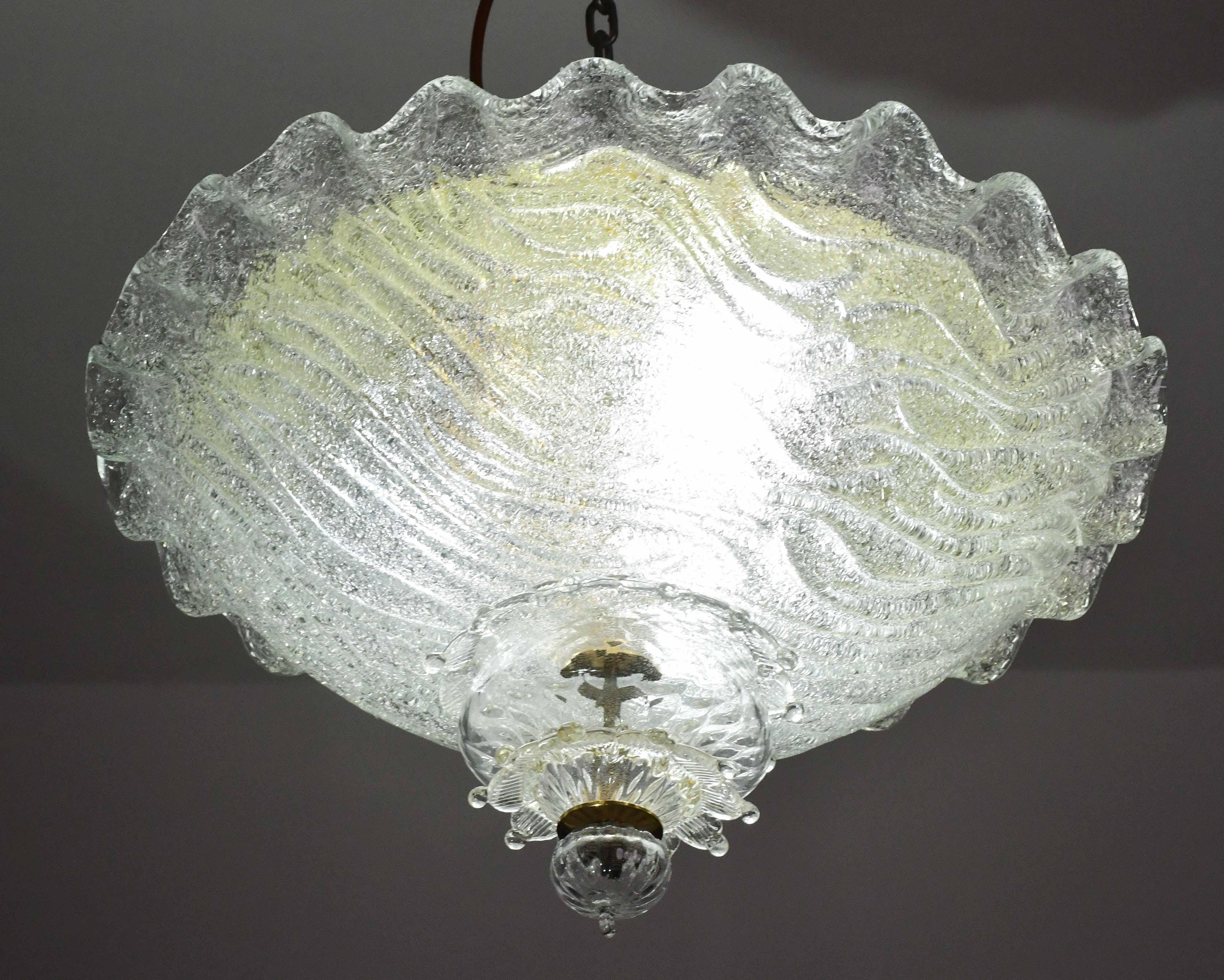 Impresionante lámpara de techo de Murano dorada y transparente con forma de corona.
La lámpara de techo consta de tres elementos de cristal, la placa central más los dos elementos bajos.
La placa central está rodeada por una franja ondulada