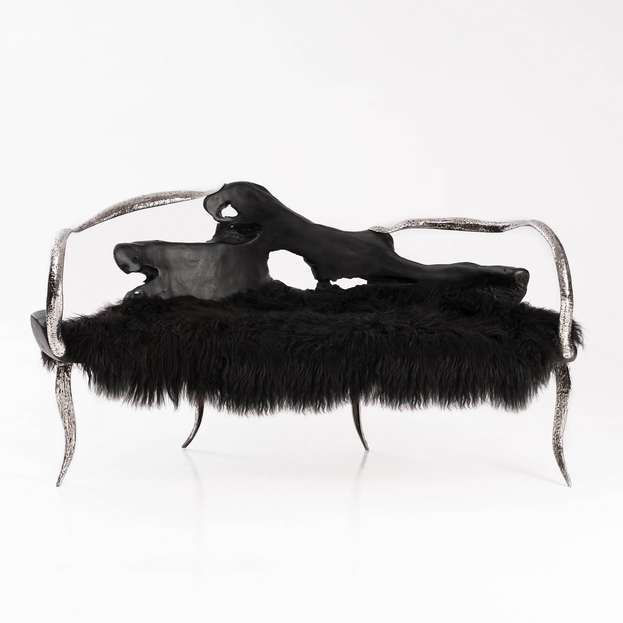 The Dark Knight Bench by Odditi
Dimensions: W 179 x D 85 x H 95 cm
Materials: FSC Certified Teak,  Icelandic Sheepskin, SS304 Grade Stainless Steel

A sleek, shadowy, organic silhouette. The Dark Knight steals the show with its bold sculptural form,