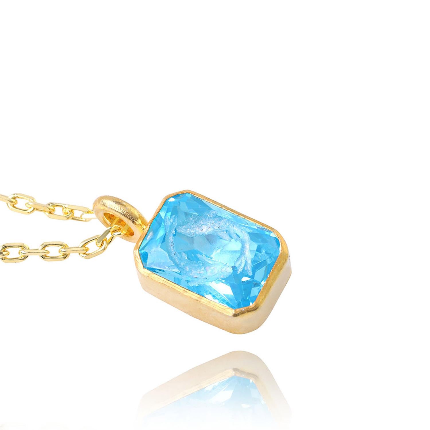 Die Duality Charm-Halskette ist nach den beiden Koi-Fischen benannt, die von Hand auf den blauen Topas-Edelstein mit 22-karätigem Gold Vermeil auf 925er Sterlingsilber gemeißelt wurden, um den sehr beliebten Glauben an Yin und Yang zu ehren. Bei Yin