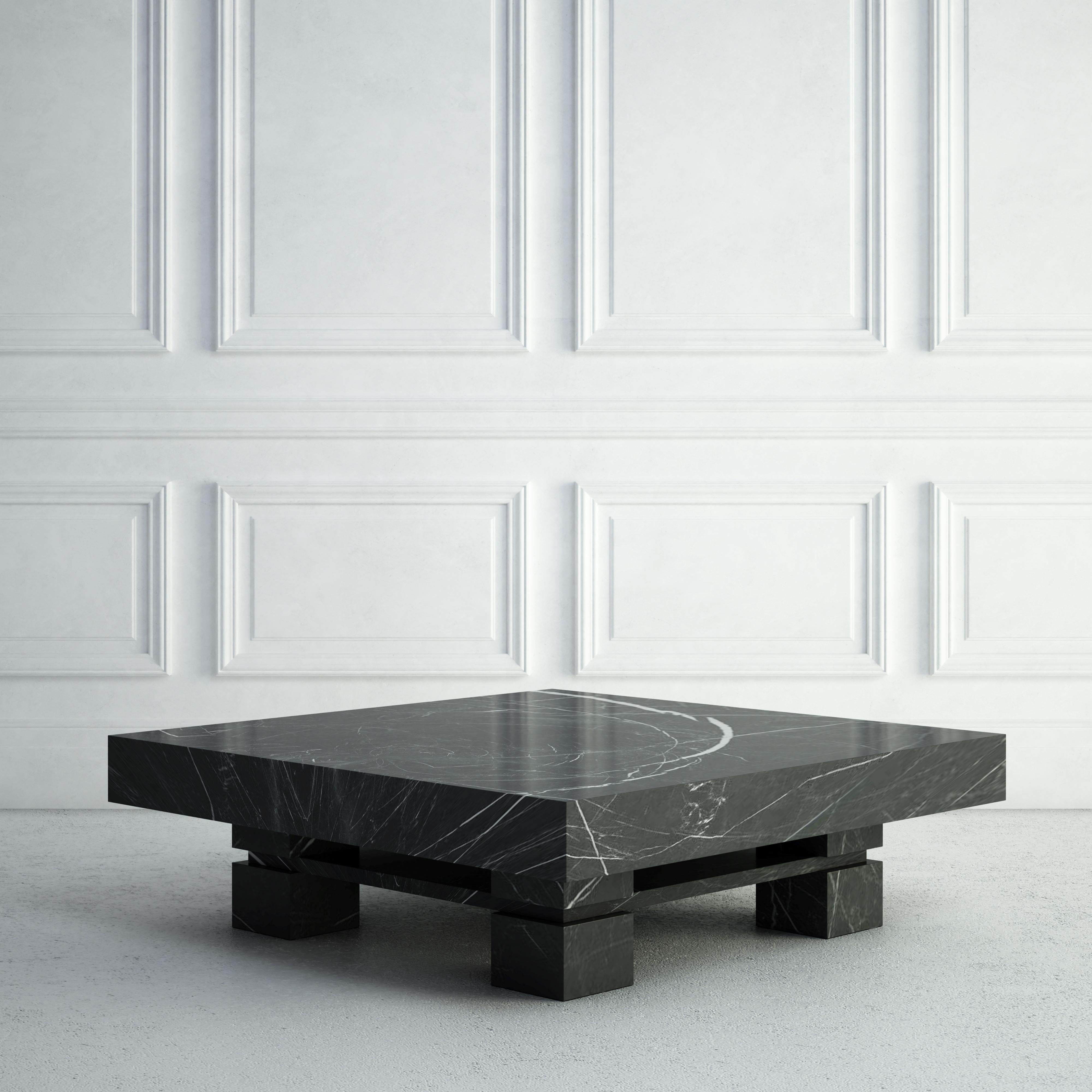 The Elodie is a bold stone coffee table that can anchor any seating area:  Its top is a thick square slab, and four chunky square bases are below, one in each corner.  A thinner square slab of the same stone breaks up each base, and runs below the