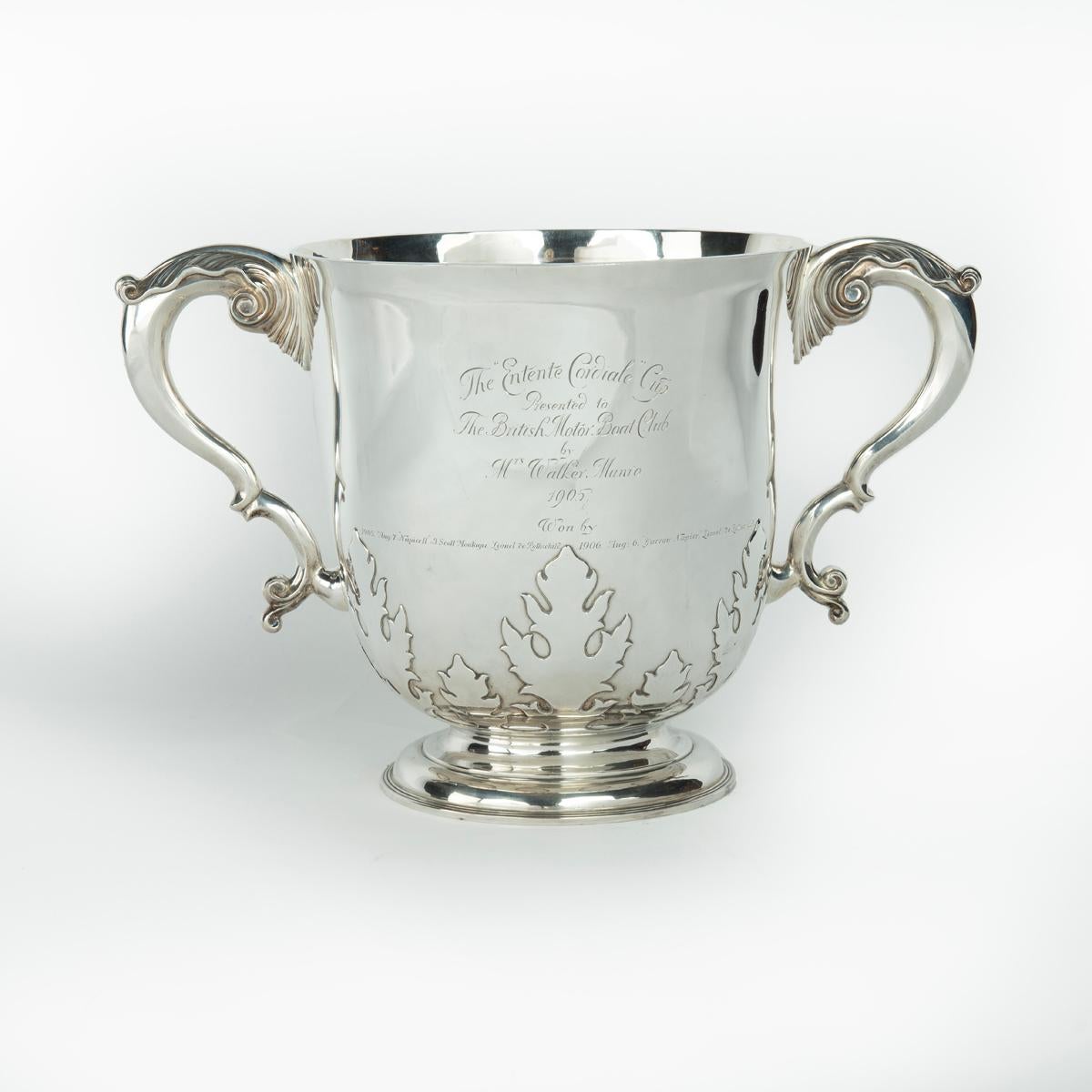 The ‘Entente Cordial’ silver champagne cooler for the British Motor Boat Club, 1905. This deep cylindrical bowl by Charles Townley and John Thomas is of heavy gauge with a raised circular foot, two acanthus scroll handles and cut-card acanthus
