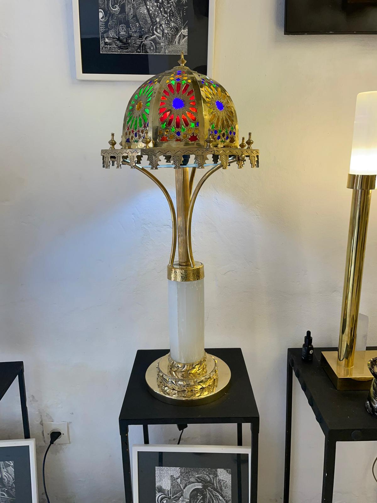 This is a beautifully hand crafted, brass, selenite crystal, and stained glass table lamp. It has a range of different textures, shapes and details which gives the lamp a great deal of depth.

From the textured horizontal lines down the shaft of the
