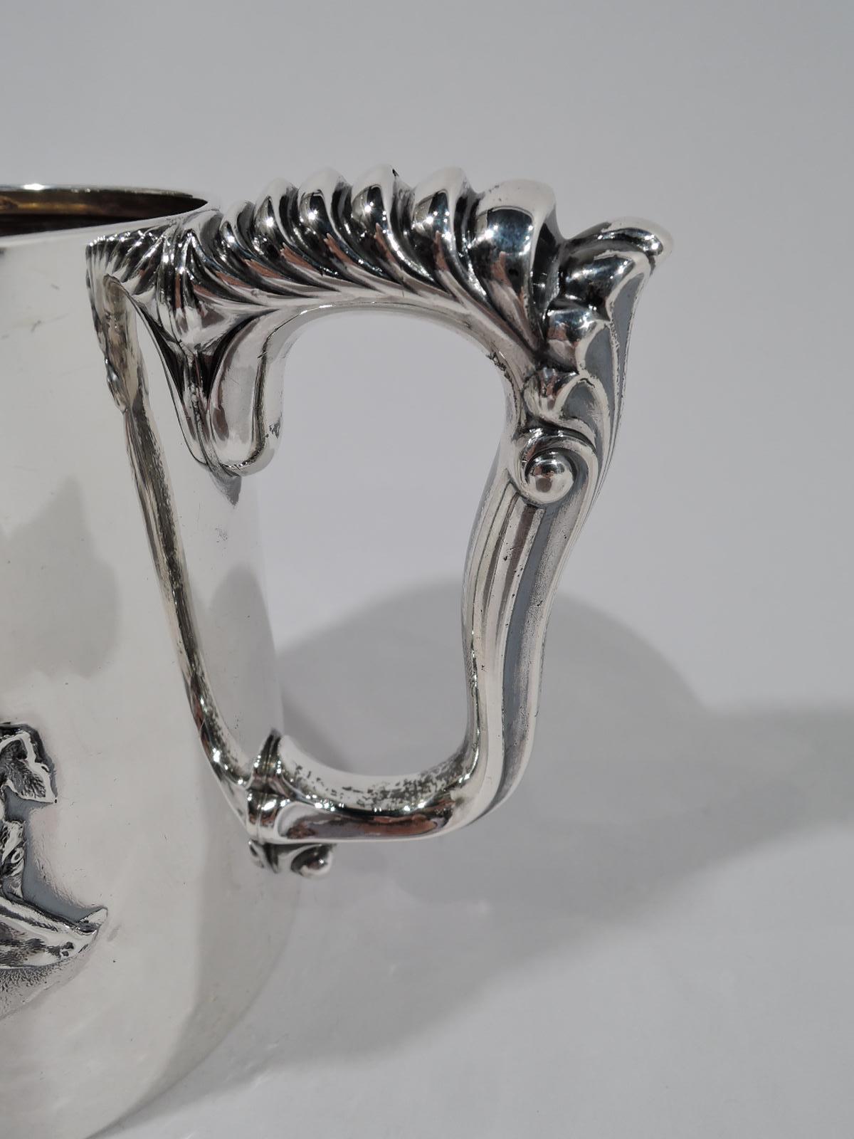 Victorian sterling silver baby cup. Made by Gorham in Providence in 1887. Straight sides and fancy fluid bracket handle with graduated gadrooning and scallop-shell thumb rest. Chased ornament: Four expressive dog heads. A canine medley, each doggy