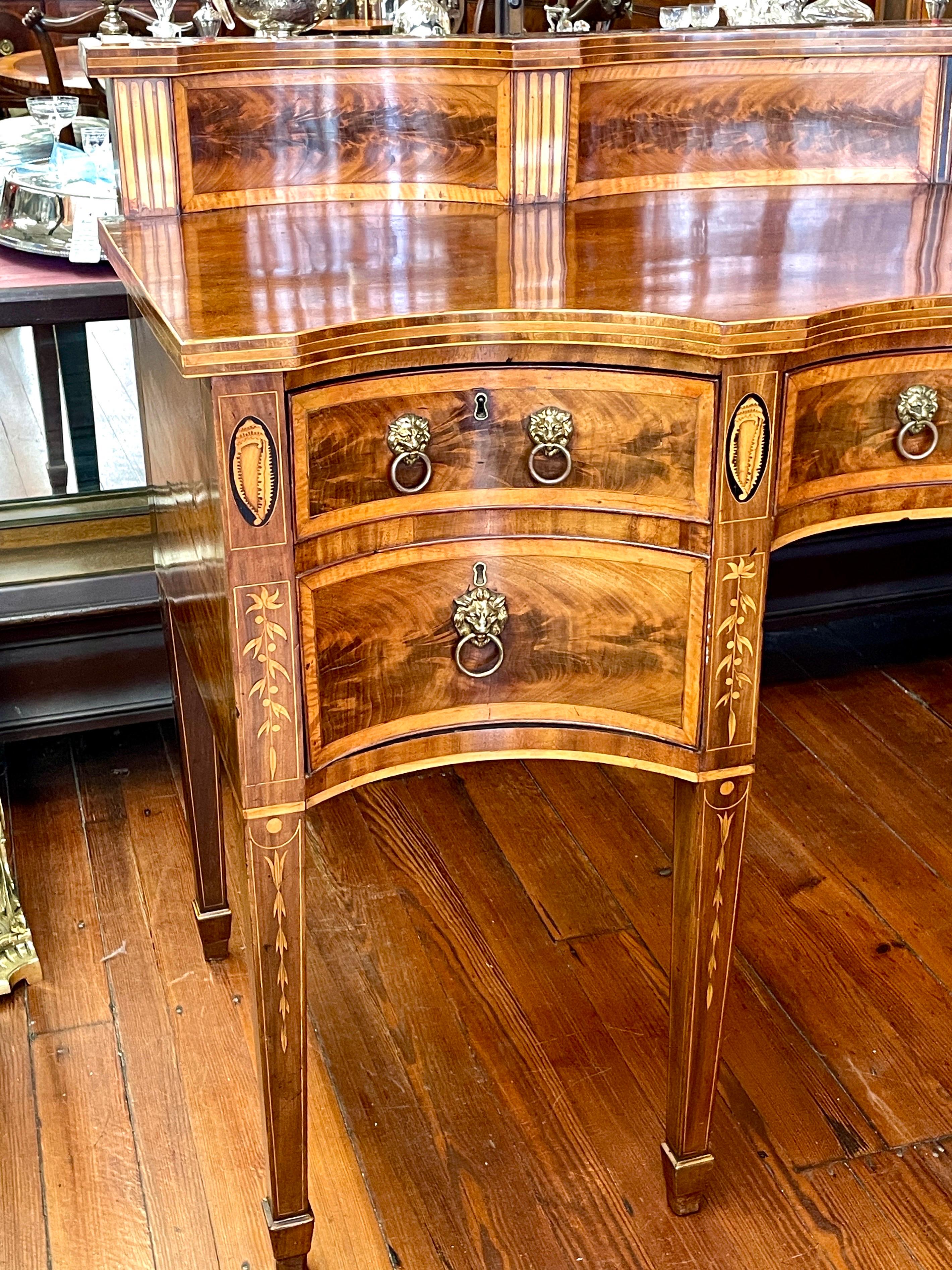 This Antique English Geo. III inlaid and highly figured book-matched flame or crotch mahogany Hepplewhite style serpentine Sideboard is quite possibly the best sideboard we have ever had - or at least the best sideboard we have had in the past fifty
