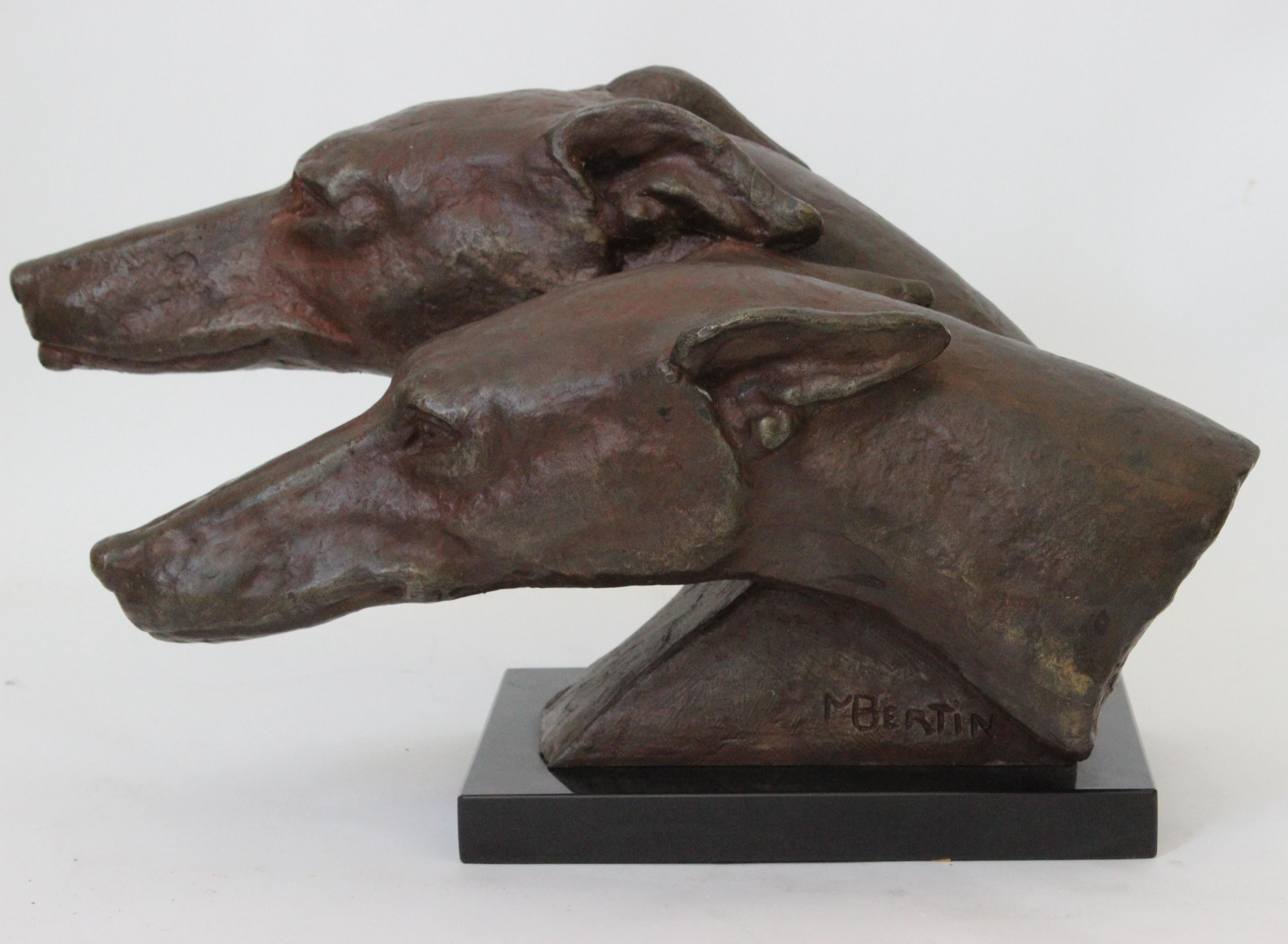 This stylish and dramatic bronze patinated metal sculpture of two grey hounds dates to the 20th century and is titled 