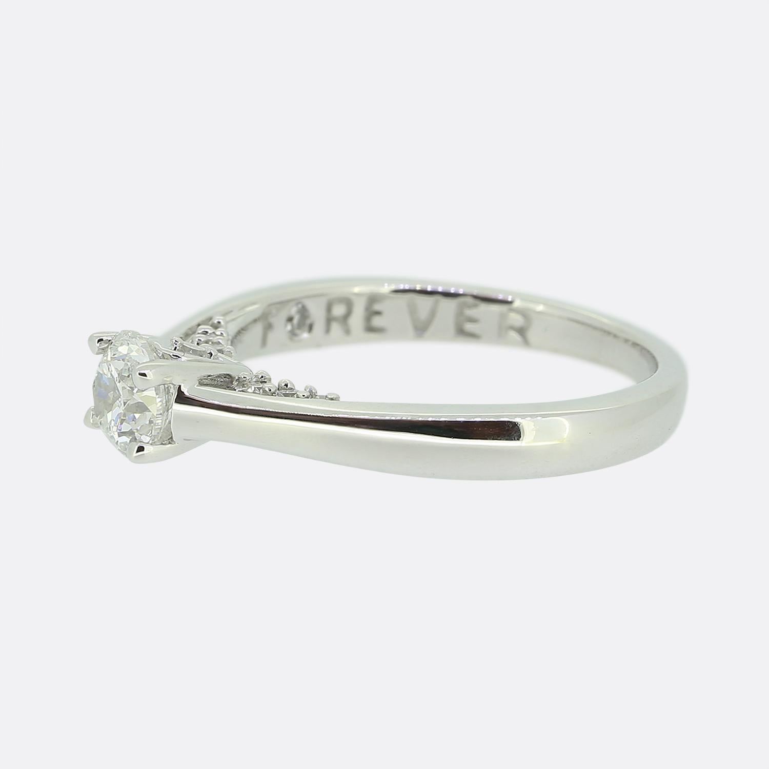 Here we have a charming 18ct white gold diamond solitaire ring from the designer 'Forever Diamonds'. The ring features a single modified brilliant cut diamond in a 4 clawed mount. A further 7 tiny matching stones can be found at either side of the