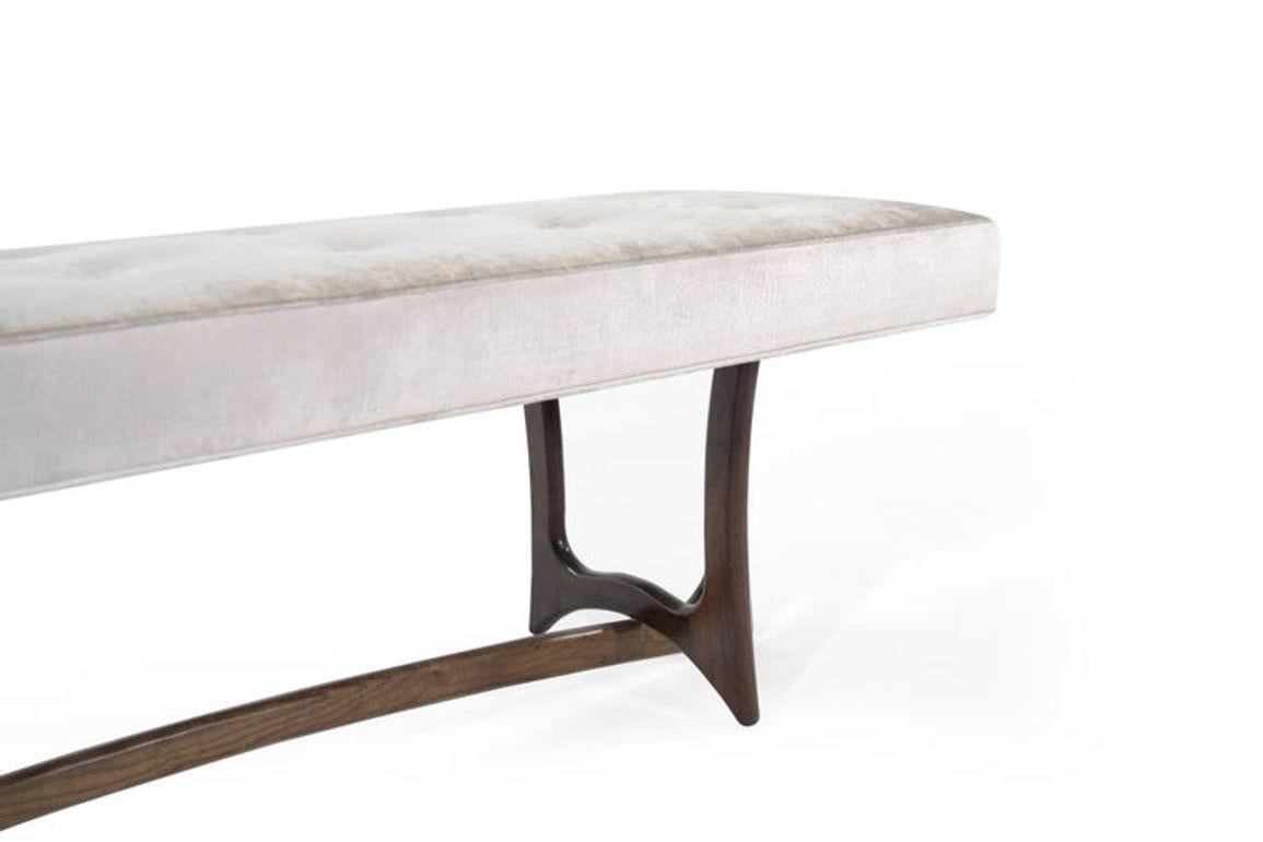 Introducing the Forma Bench by Stamford Modern—an embodiment of Mid-Century Modern elegance, seamlessly blending visionary designs by Adrian Pearsall and Vladimir Kagan. With a sculpted walnut base and plush upholstered cushion, it offers both form