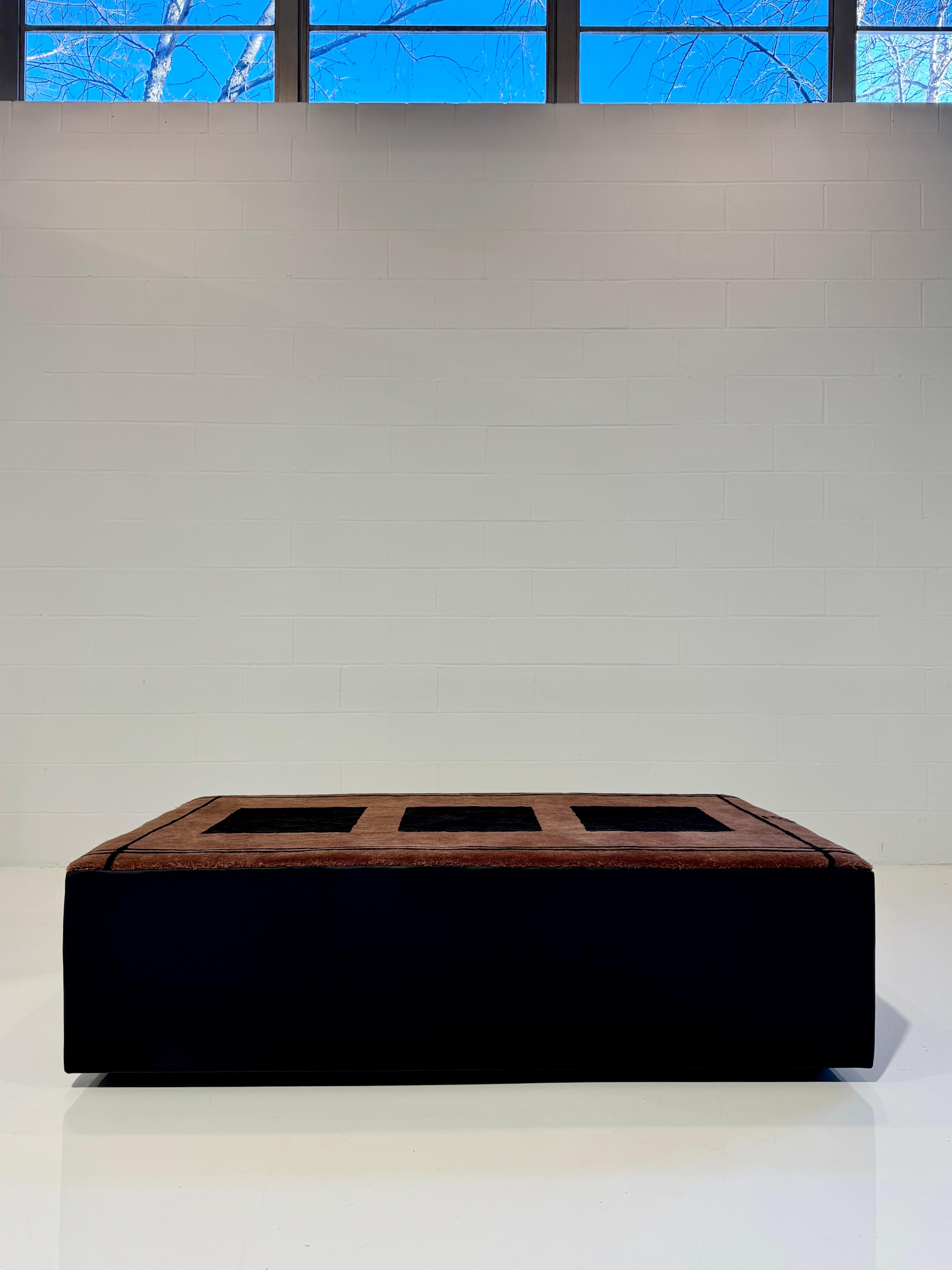 Fait partie de la Collection SYTH Originals. 

Nouveau, unique ottoman de tapis fabriqué à la main dans un tapis de laine par Zouzou Rugs et fini avec des côtés en cuir luxueux.

36 L x 62 L x 17 H po.

La table basse parfaite, l'ottoman ou le siège