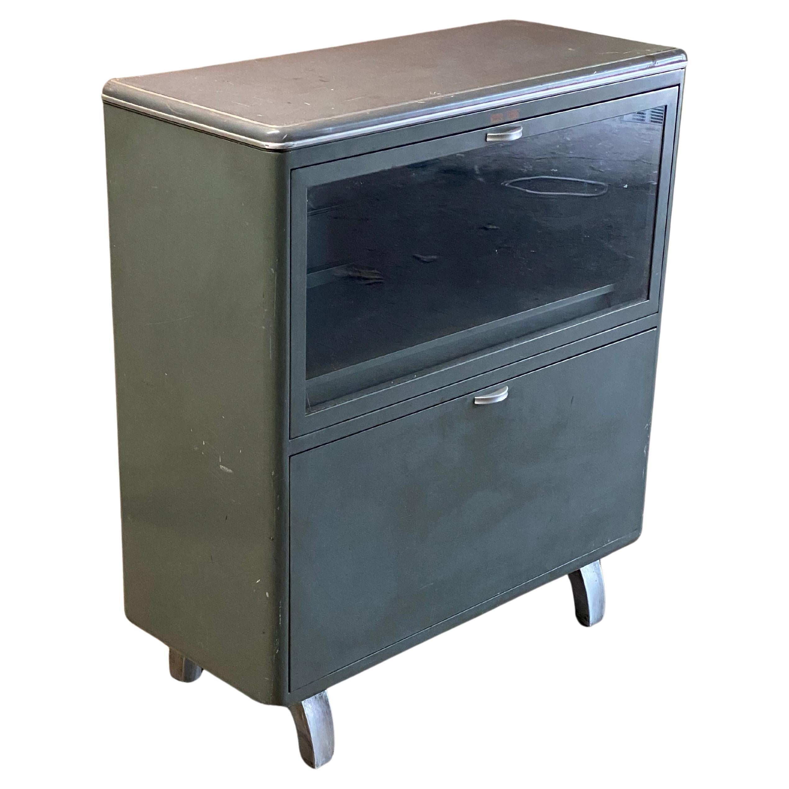 Industrial steel and glass bookcase cabinet by The General Fireproofing Company. Circa 1950. The cabinet features easy access pull down doors and extending bookshelves, four wonderful curved cast aluminum feet and rounded stream lined modern lines.