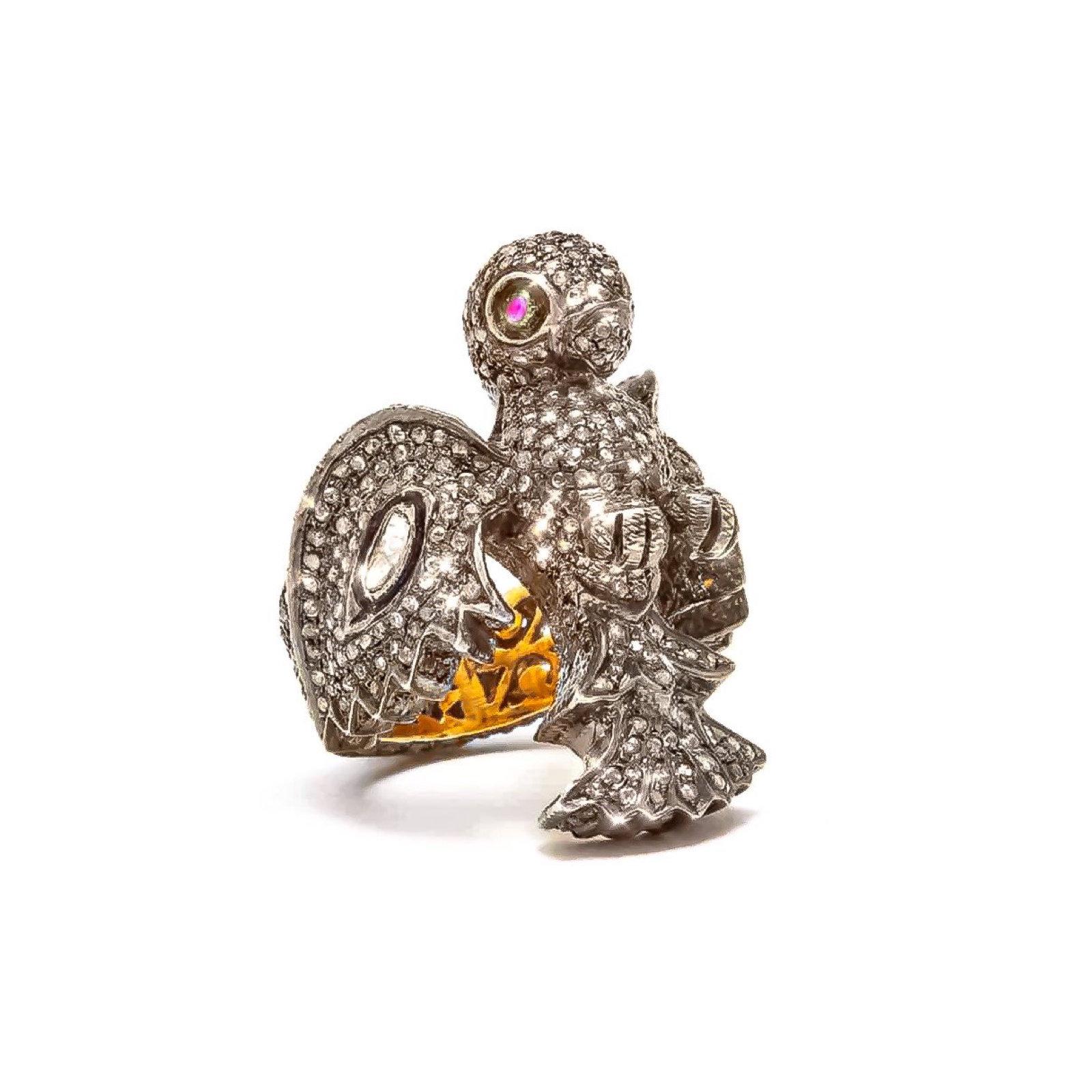 A stunning interpretation of the Goddess Laxmi’s mode of transportation, the owl. Incarnate by dazzling White Diamond wings and fiery Pink Ruby eyes in a fully Pavé Diamond ring. This beautiful ring is set in Oxidized Silver with an 18 Karat Gold