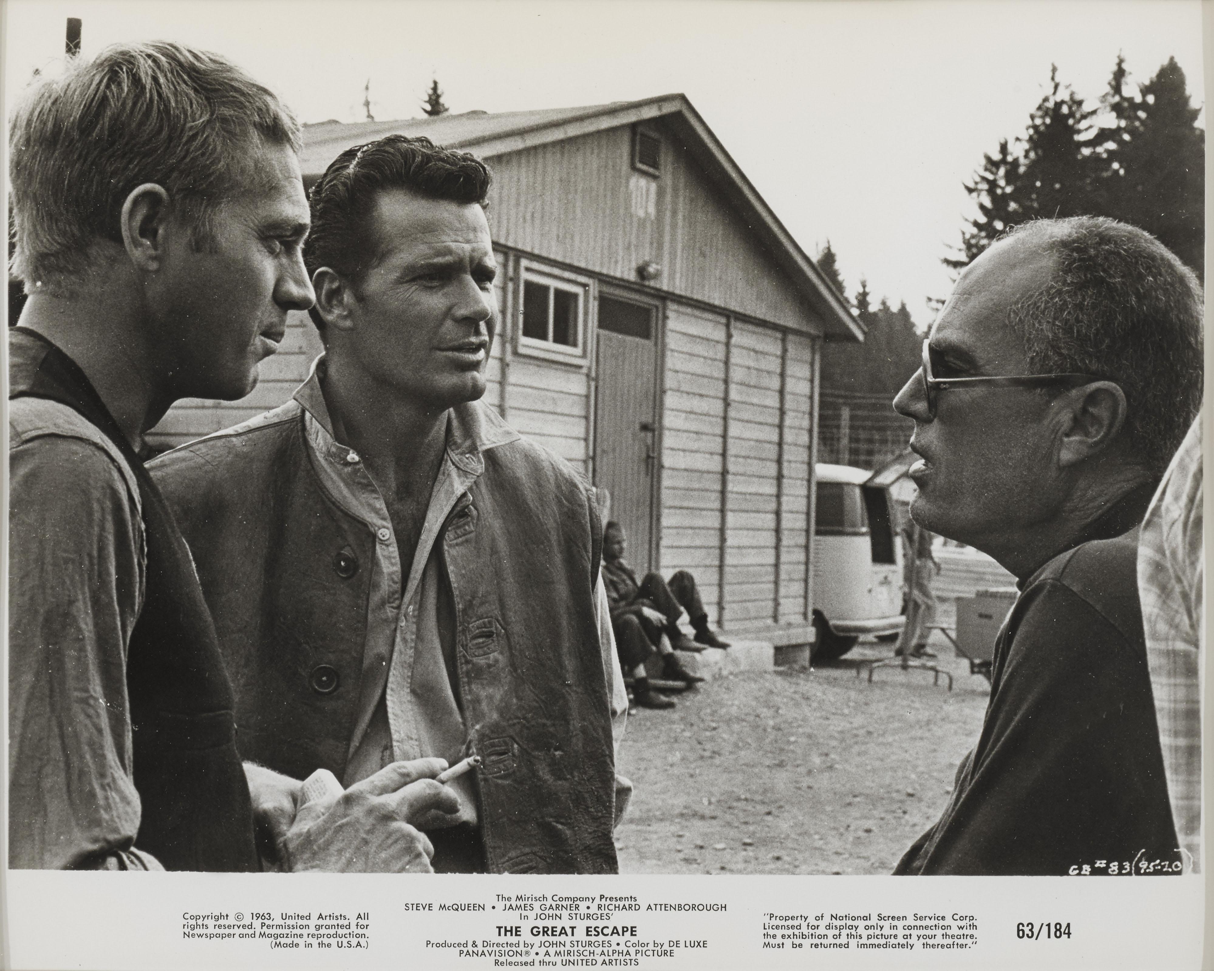 Original US-Studiofoto für John Sturges klassisches Kriegsabenteuer von 1963 mit Steve McQueen, James Coburn, James Garner und Richard Attenborough in den Hauptrollen. Dieses Foto zeigt den Regisseur im Gespräch mit Steve McQueen und James Garner am