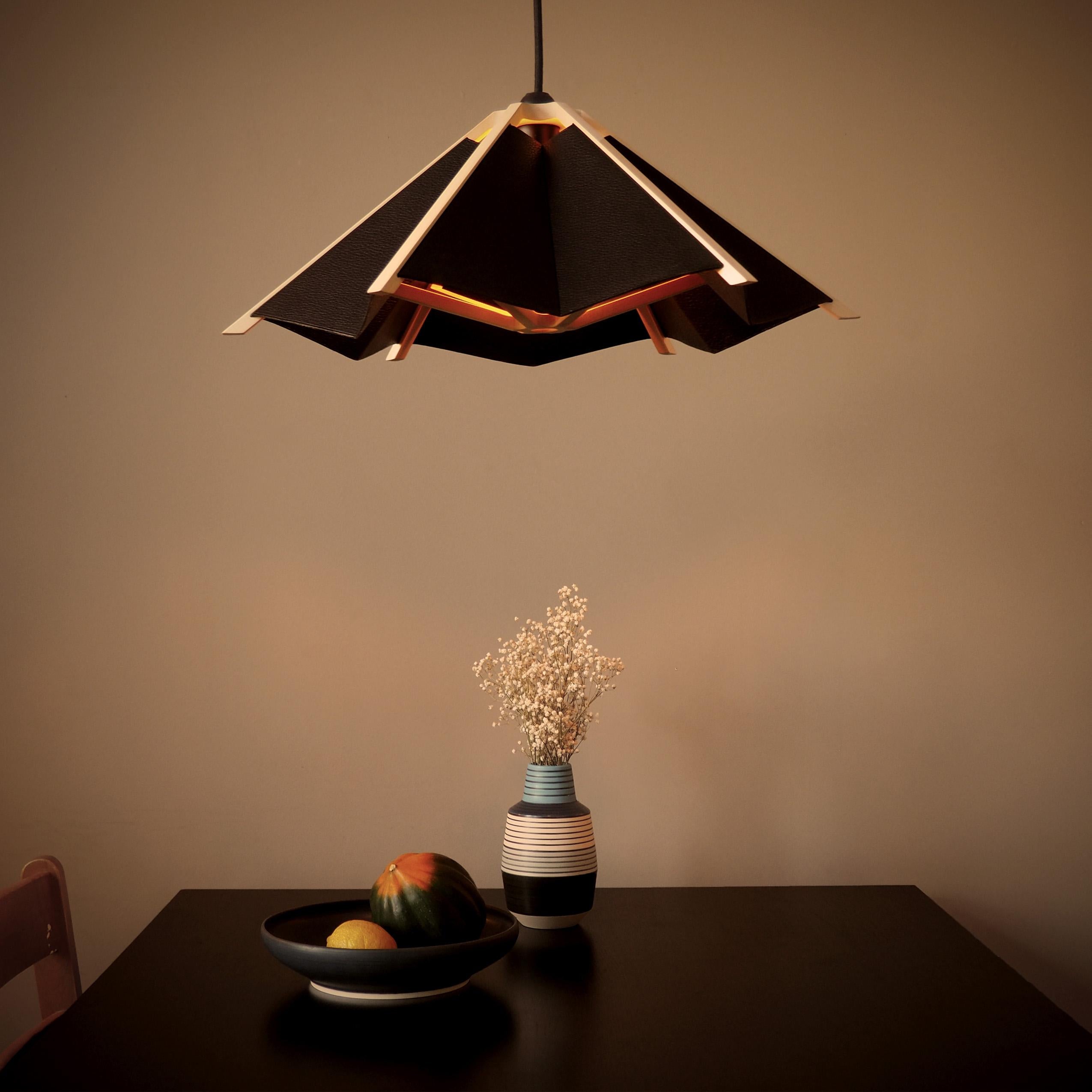 The Hanging Garden Lampshade is inspired by small paper umbrellas. 
A familiar object from our childhood, rethought as a hanging lamp. 
This lampshade has a very light wooden structure with different leather facets to create a textural contrast with
