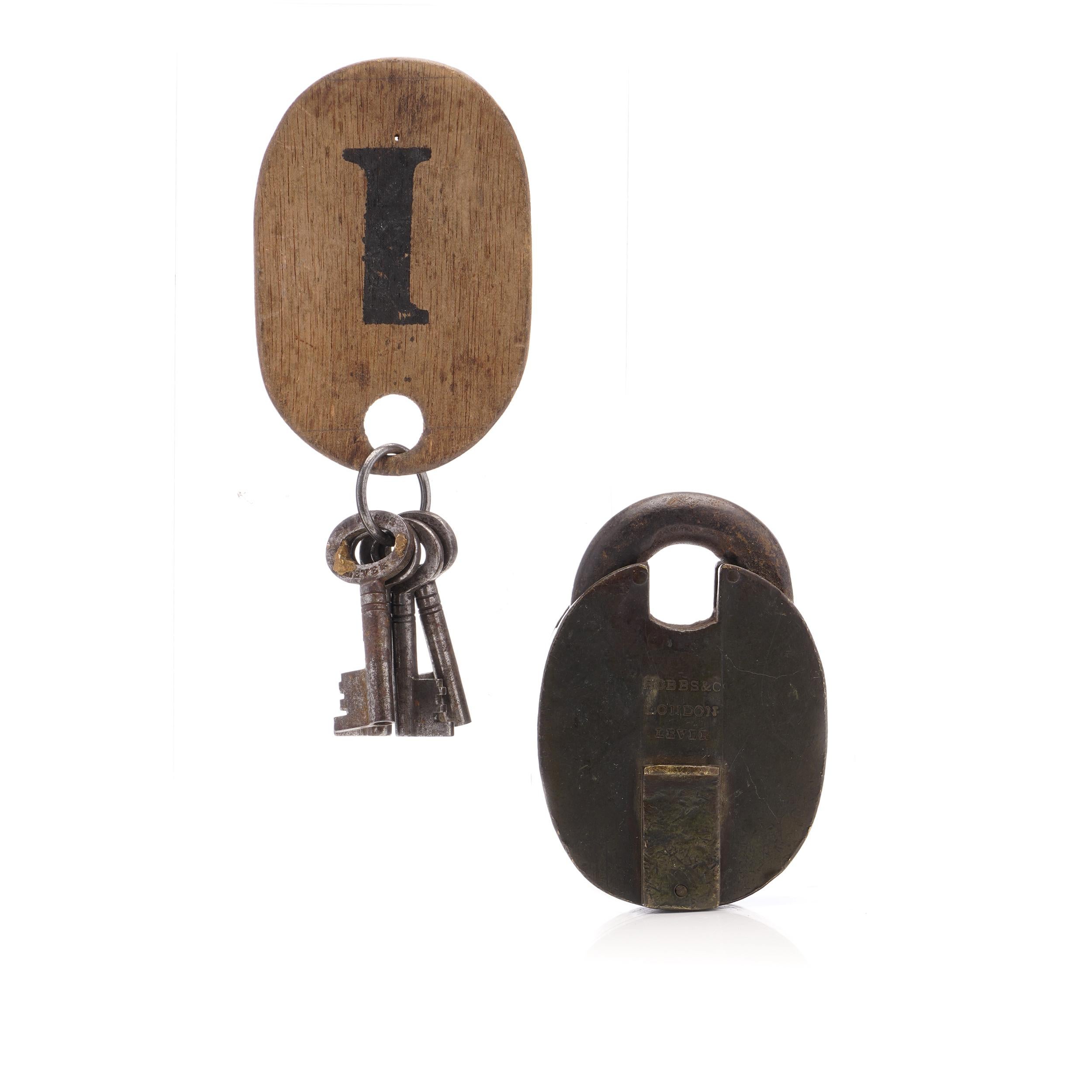 The Hobbs & Co. Le cadenas victorien en fer lourd avec sa clé d'origine est une pièce remarquable de l'histoire et de l'artisanat. Cette serrure ancienne, mesurant 9,2 cm x 6,3 cm x 2,5 cm et pesant 702 grammes, représente l'ingéniosité de son