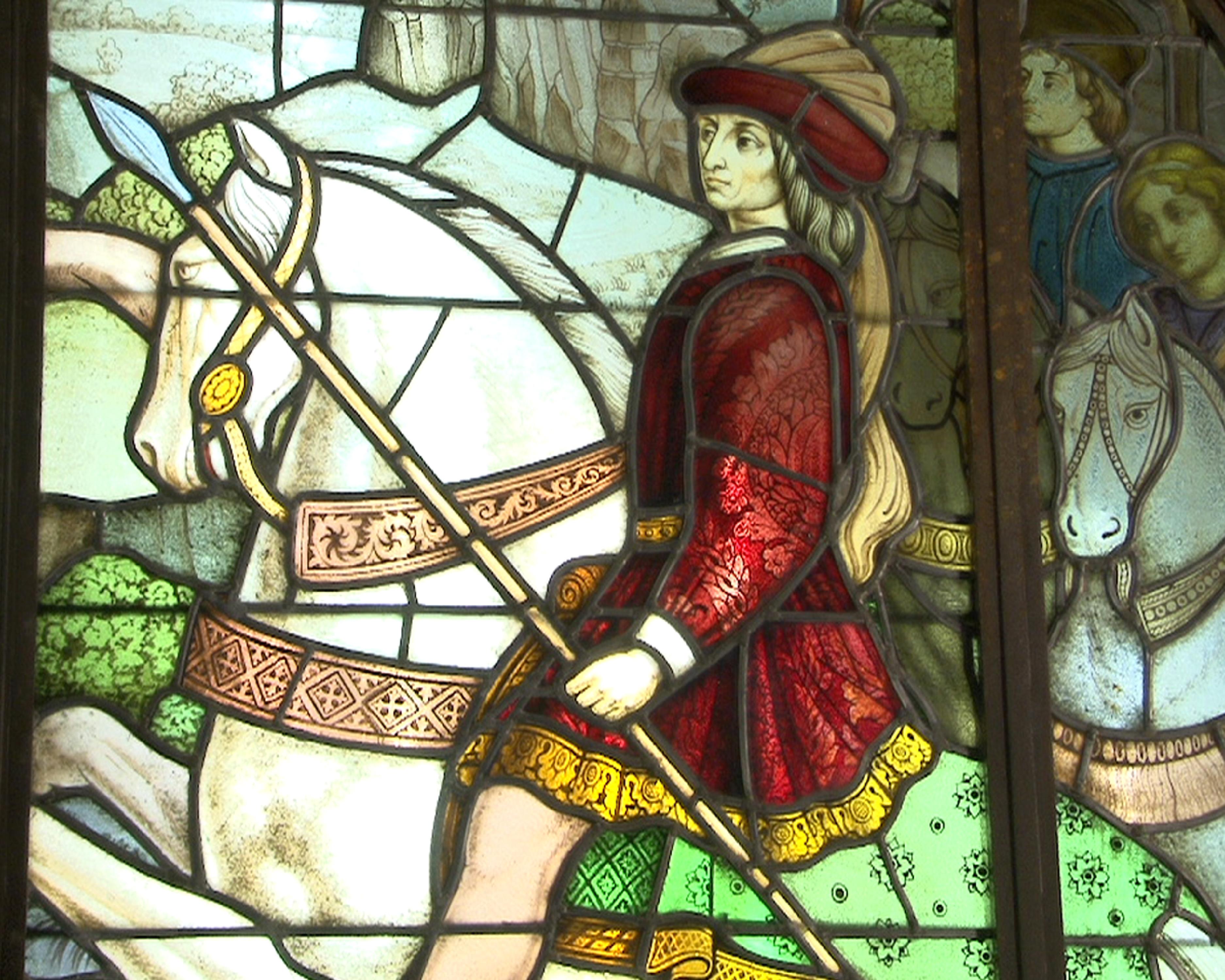Dieses große Glasfenster im neugotischen Stil zeigt eine große Jagdszene mit zwei Männern auf ihren Pferden, die Hirsche jagen. Beide Männer, wohlhabende Knappen, tragen mittelalterliche Kostüme, wie bestickte Tunika, Federhut und lange Sporen. Ein
