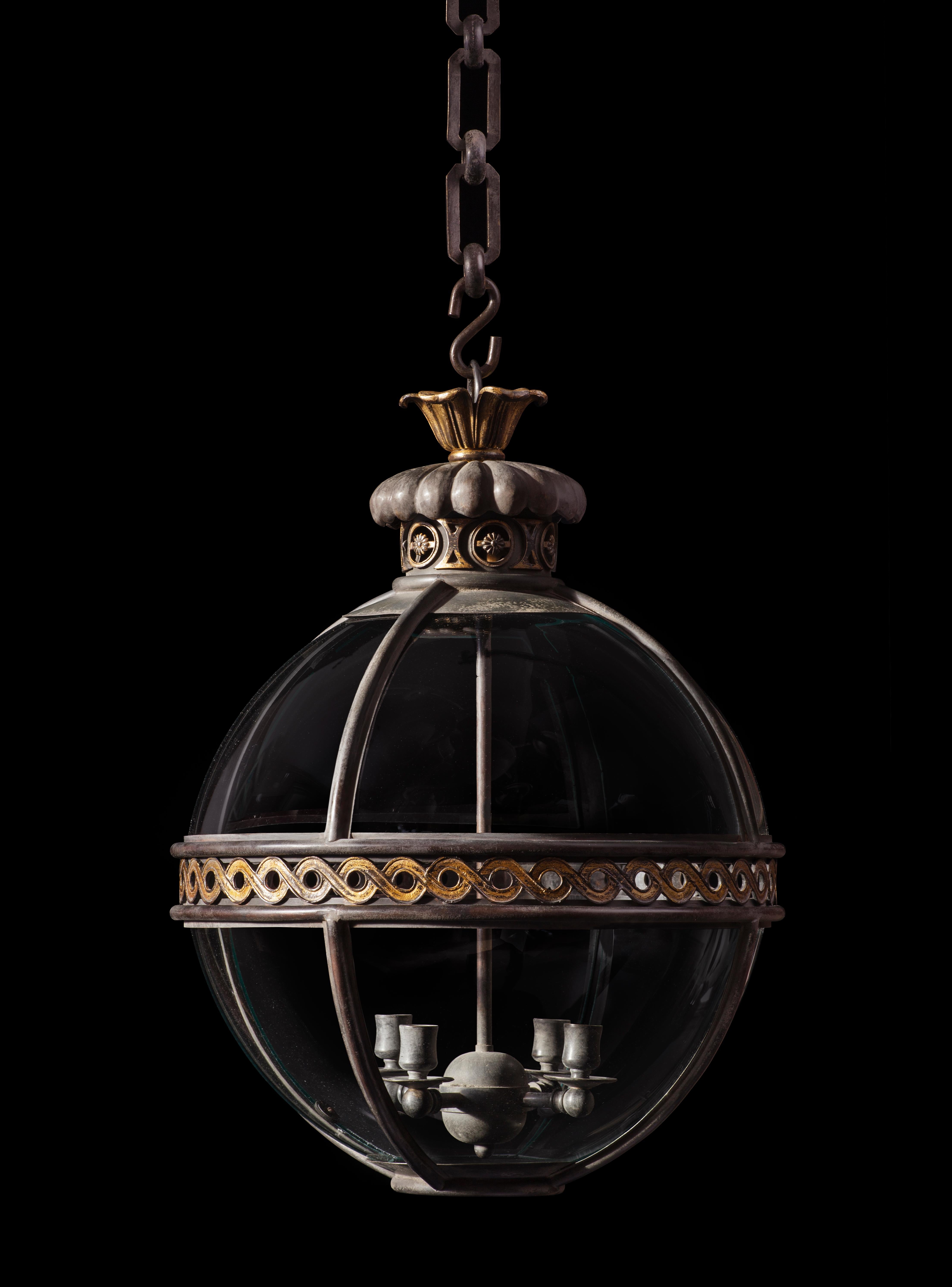 Each of the eight glass panes sit within bronze mouldings divided by a meridian band of pierced gilt brass guilloche. The gadroon – moulded chimney with flower head filled, gilt brass guilloche sits beneath a leaf cast rose.
 
 