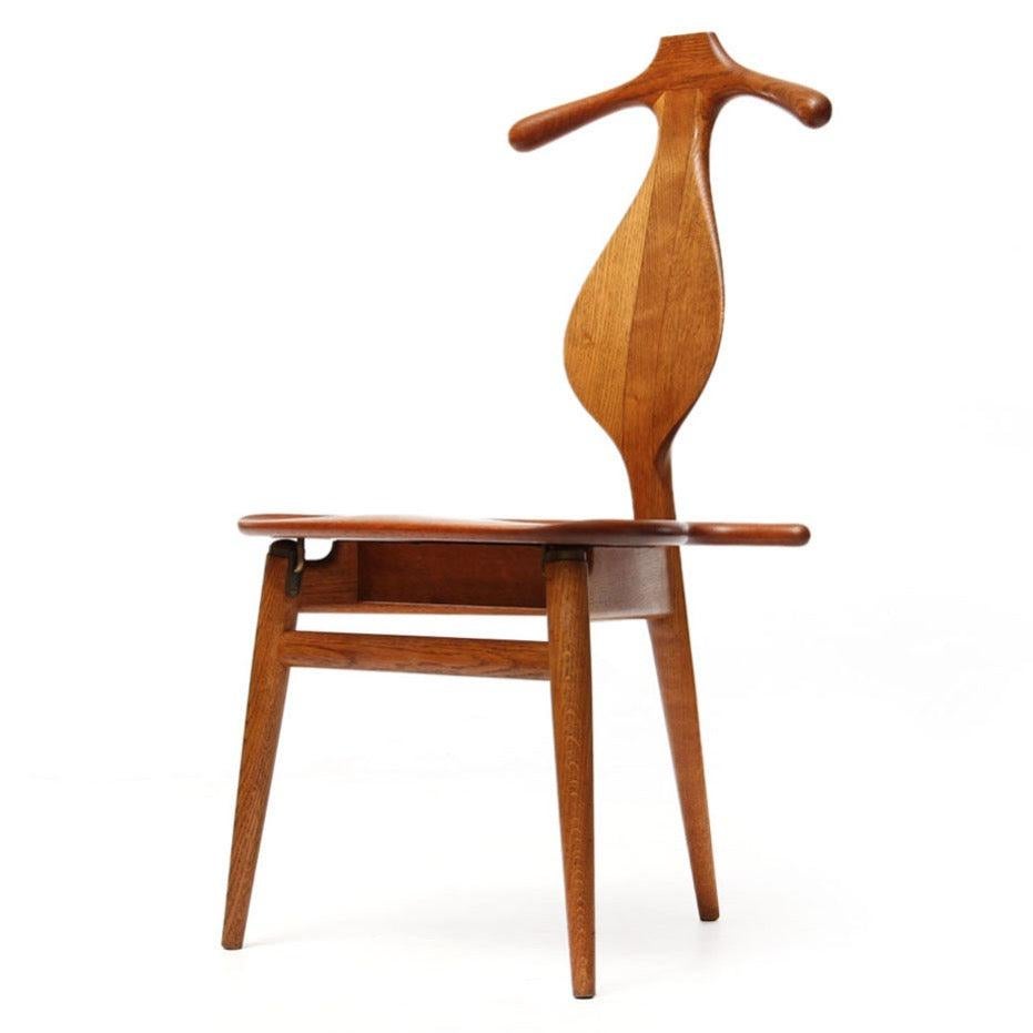 Iconic Wegner JH 250 'Valet' chair executed in solid oak and teak. The shaped crest rail sitting above a leaf shaped back acts as a shirt hangar while the hinged seat opens forward to provide a rest for draped pants. The seat when open reveals box