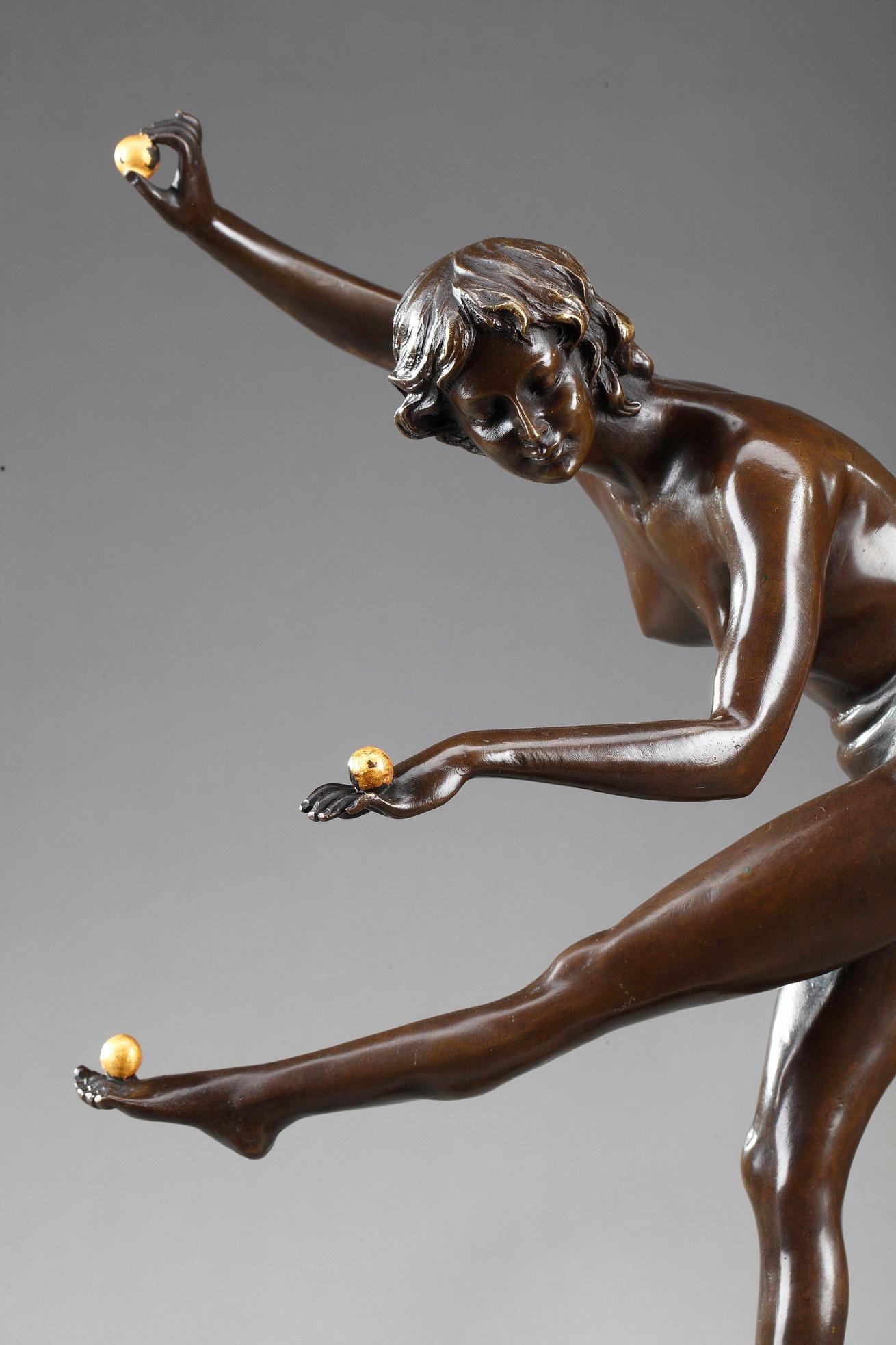 Bronze sculpture with brown patina featuring a young woman juggling three gilded balls, on a small circular base. The base is chiseled with foliage and small pearls. The bronze is set upon a black marble plinth. Signed Cl. JR COLINET and Bronze