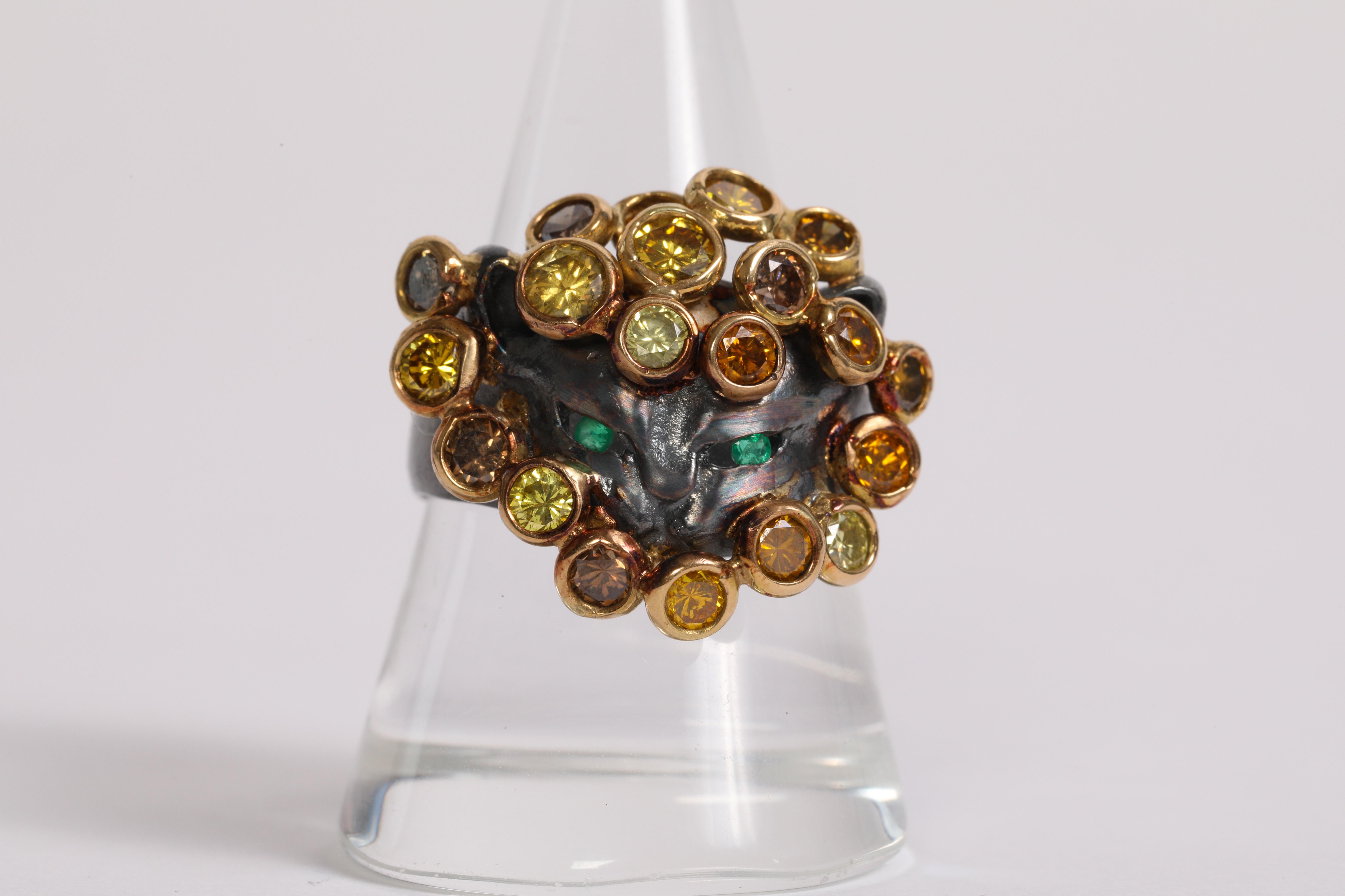 A unique ring representing the head of a cat with emerald in the eyes and diamonds around the neck
We have made a camaieu of yellow, green, orange and brown diamonds, set in 18 K yellow gold.
The ring body is in black silver. 
Size 56- US 7