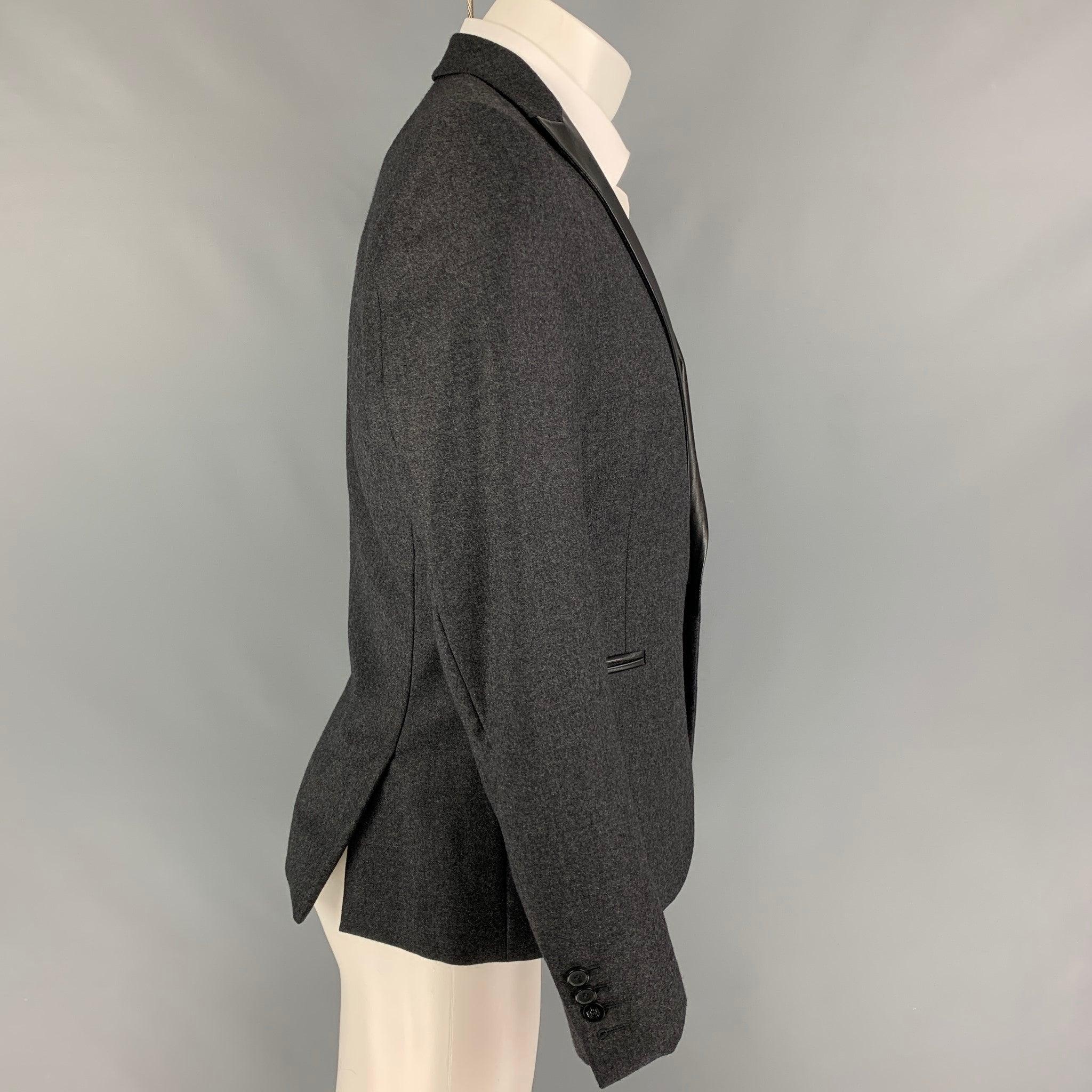 THE KOOPLES sport coat comes in a charcoal wool with a full liner featuring a leather peak lapel, slit pockets, double back vent, and a single button closure.
Very Good
Pre-Owned Condition. 

Marked:   48 

Measurements: 
 
Shoulder: 17 inches 