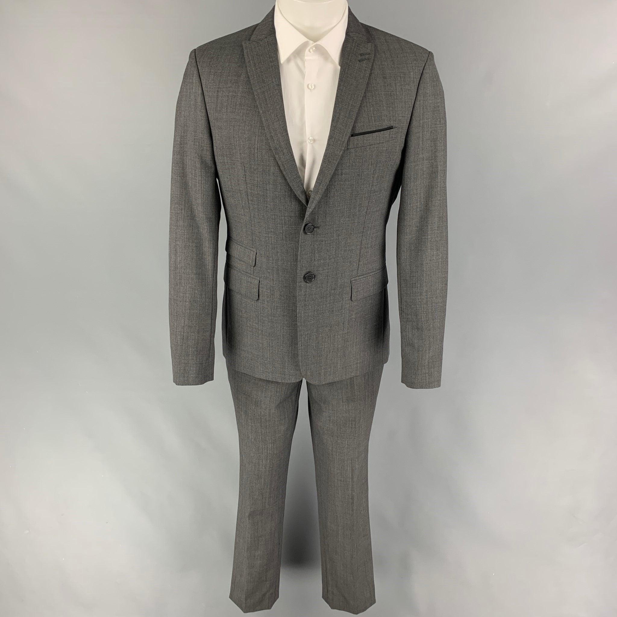 THE KOOPLES
suit comes in a dark gray wool with a full liner and includes a single breasted, double button sport coat with a peak lapel and matching flat front trousers. Very Good Pre-Owned Condition. 

Marked:   48 

Measurements: 
 