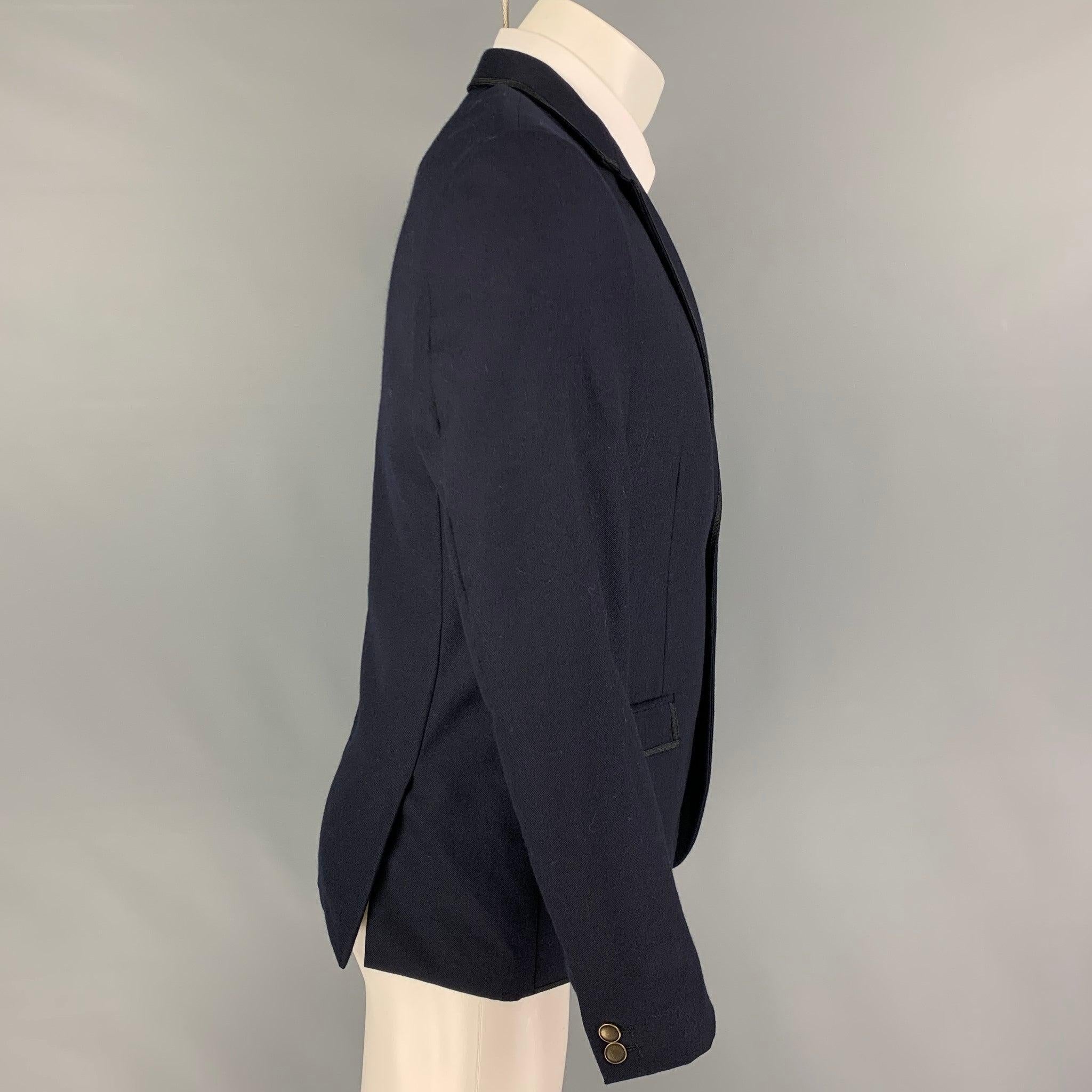 THE KOOPLES
sport coat comes in a navy wool with a full liner featuring a notch lapel, flap pockets, beaded skull head crest patch, double back vent, and a double button closure.Very Good Pre-Owned Condition.  

Marked:   48 

Measurements: 
