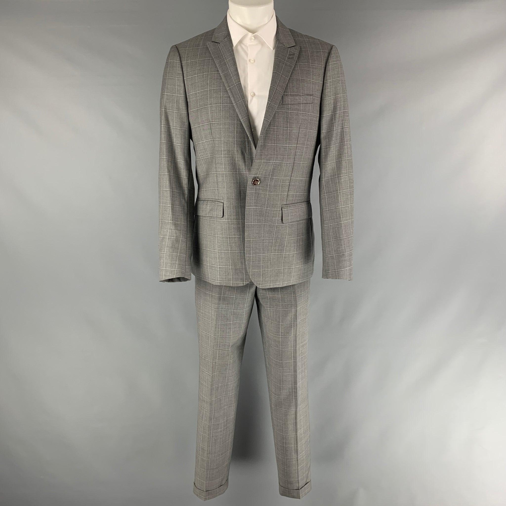 THE KOOPLES suit comes in a grey window pane wool woven material with a full liner and includes a single breasted, single button style with a peak lapel and matching fitted flat front trousers.Excellent Pre- Owned Condition. 

Marked:   40 