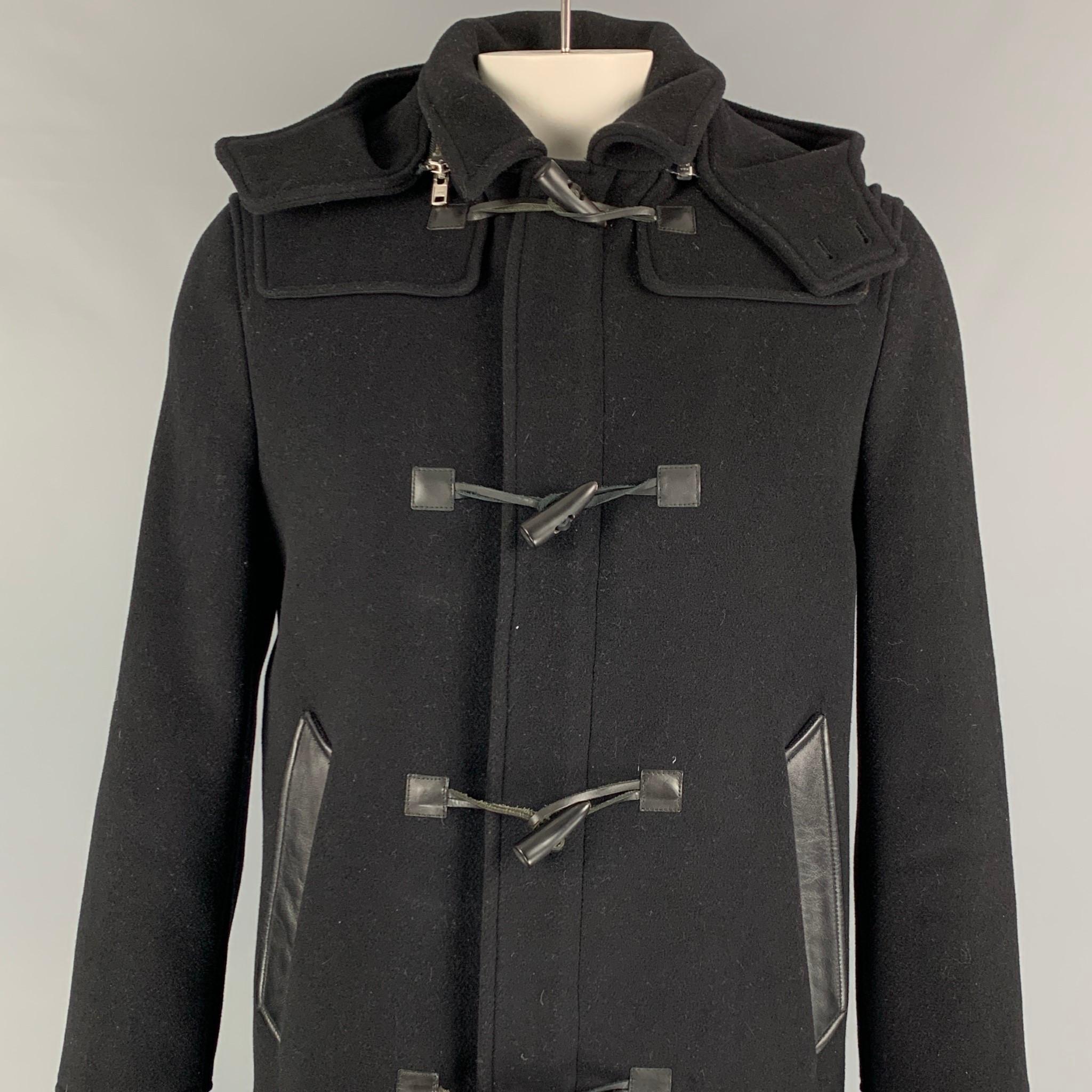 THE KOOPLES coat comes in a black wool with a full quilted liner featuring a removable hood, spread collar, leather trim, slit pockets, single back vent, and a toggle button closure. 

Very Good Pre-Owned Condition.
Marked:
