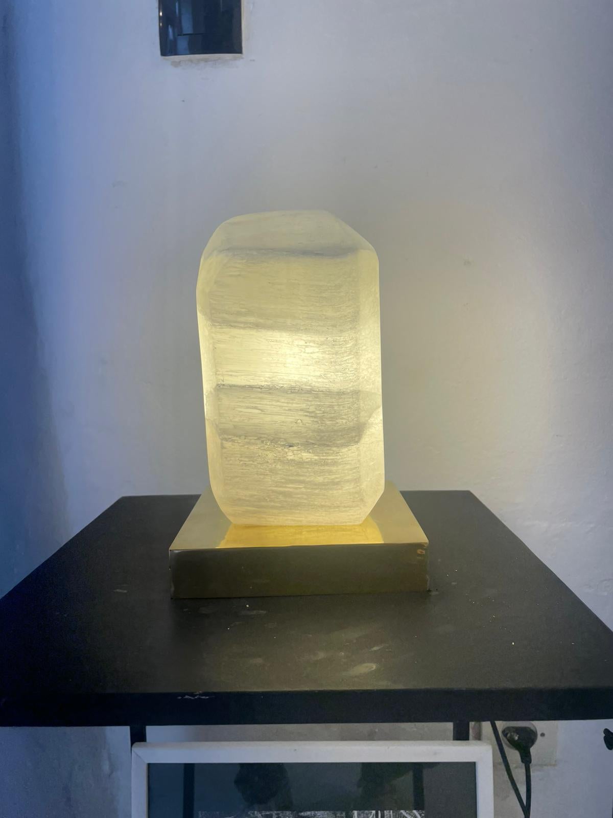 This stunning table lamp features a harmonious blend of brass and selenite rock crystal. The crystal has been expertly shaped and polished to a smooth, rounded form, giving it a soft and elegant appearance.

With the light source positioned at the