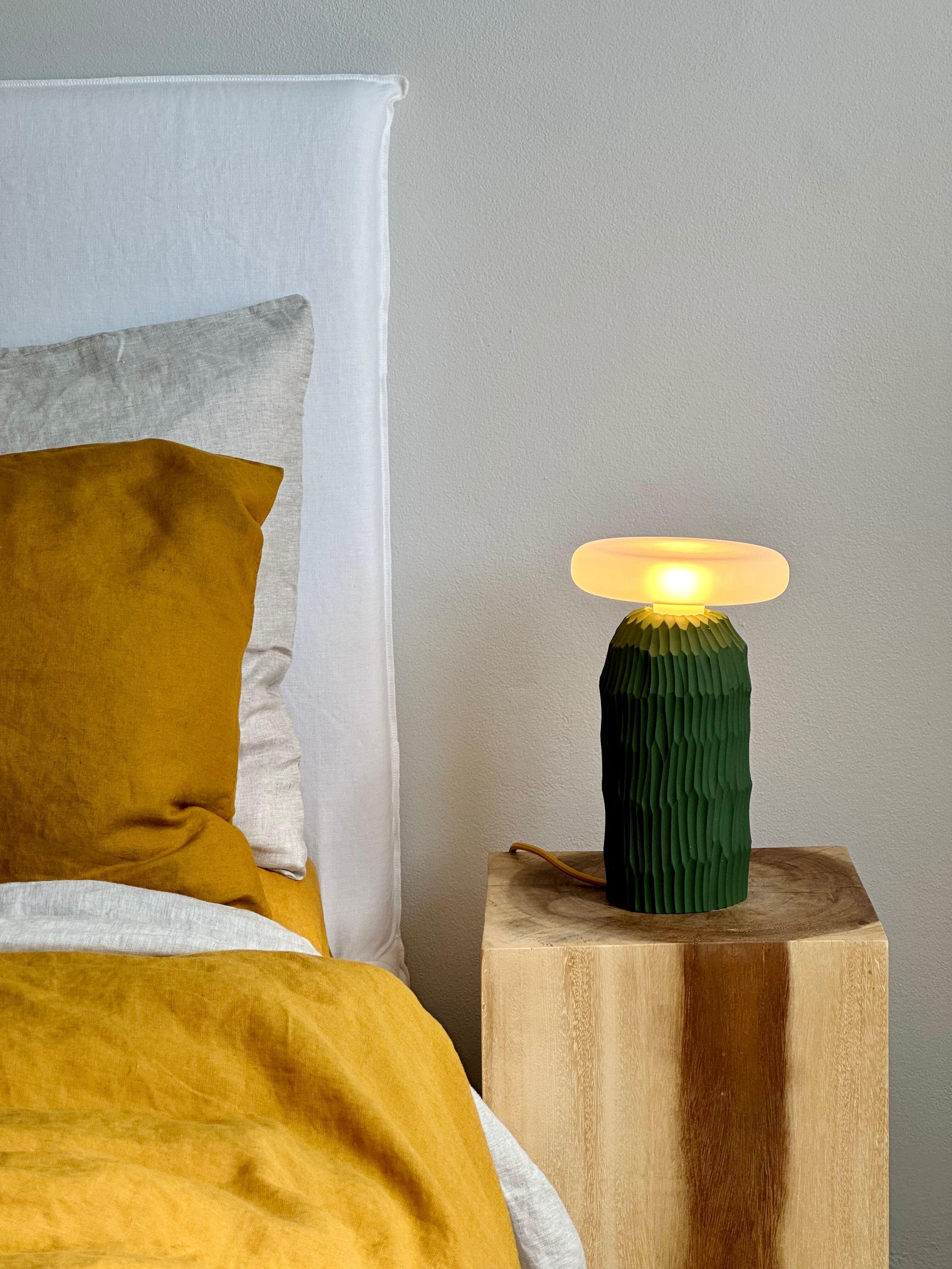 The lamp is a simple and minimalist hand formed ceramic table lamp without a lampshade. Its unique textural base is hand carved in a signature design, with a distinct natural grain from its clay origins. 
It has been designed to create a unique