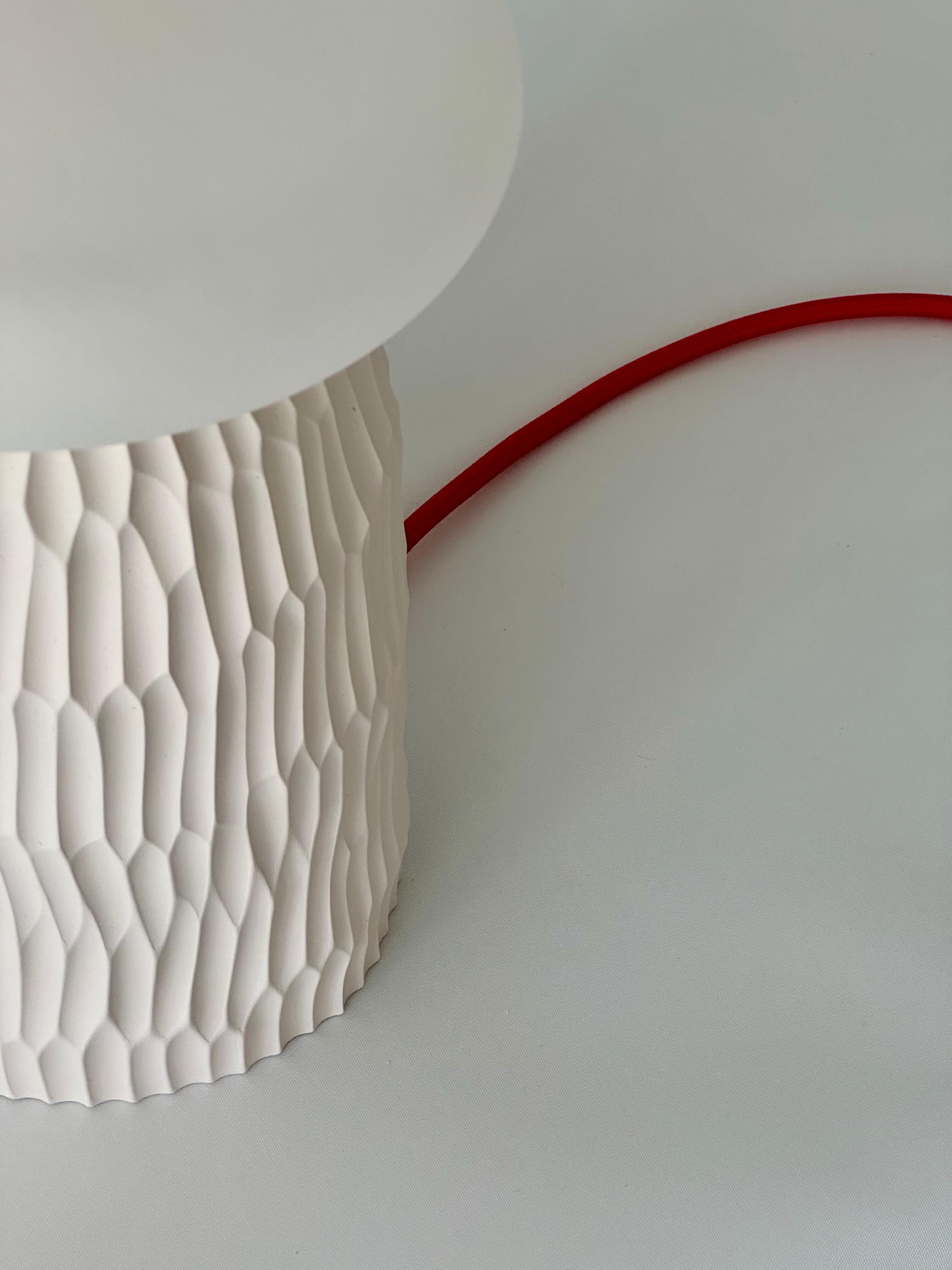 The lamp is a simple and minimalist hand formed ceramic table lamp without a lampshade. Its unique textural base is hand carved in a signature design, with a distinct natural grain from its clay origins. 
It has been designed to create a unique