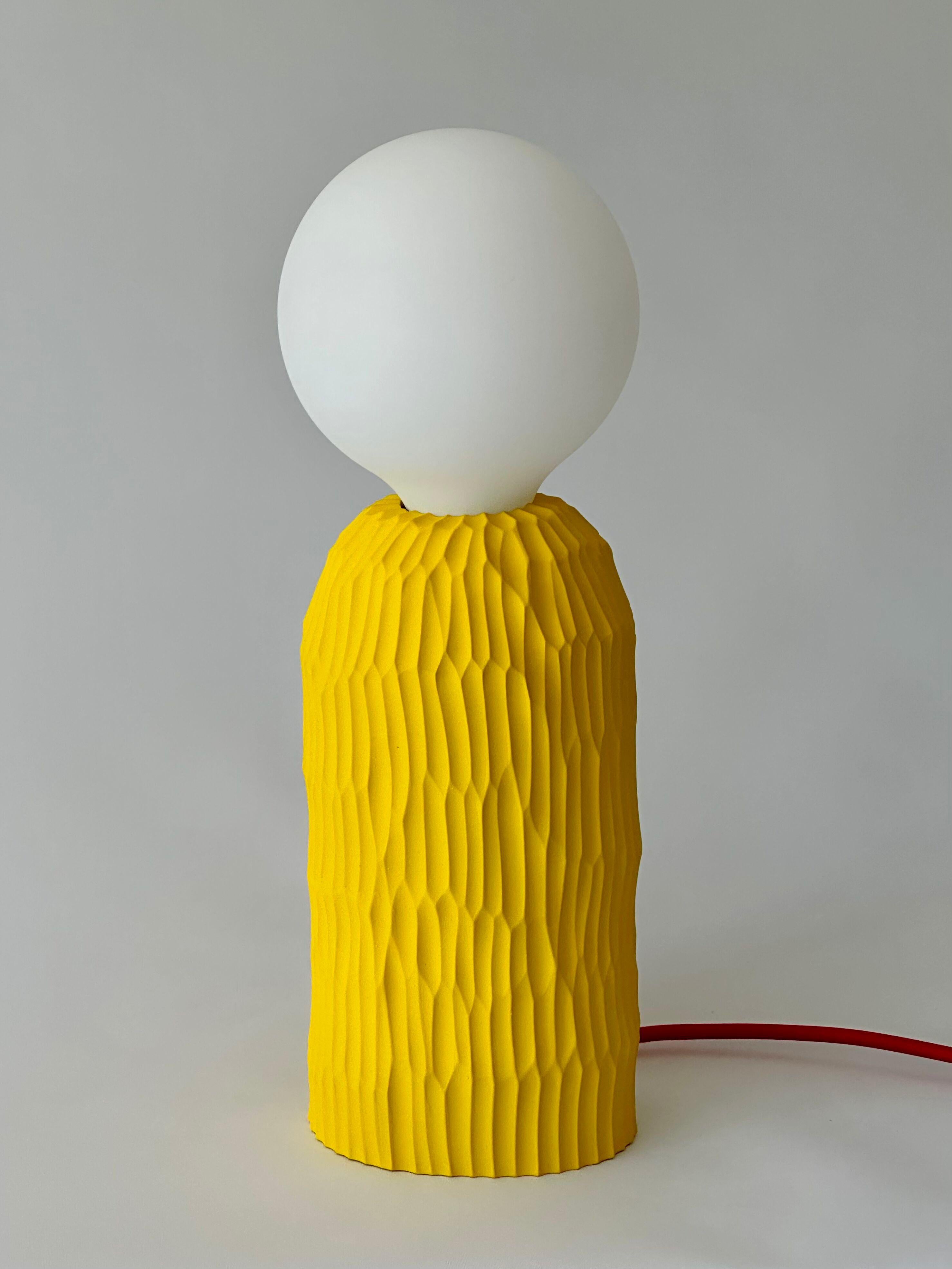 The lamp is a simple and minimalist hand formed ceramic table lamp without a lampshade. Its unique textural base is hand carved in a signature design, with a distinct natural grain from its clay origins.

It has been designed to create a unique