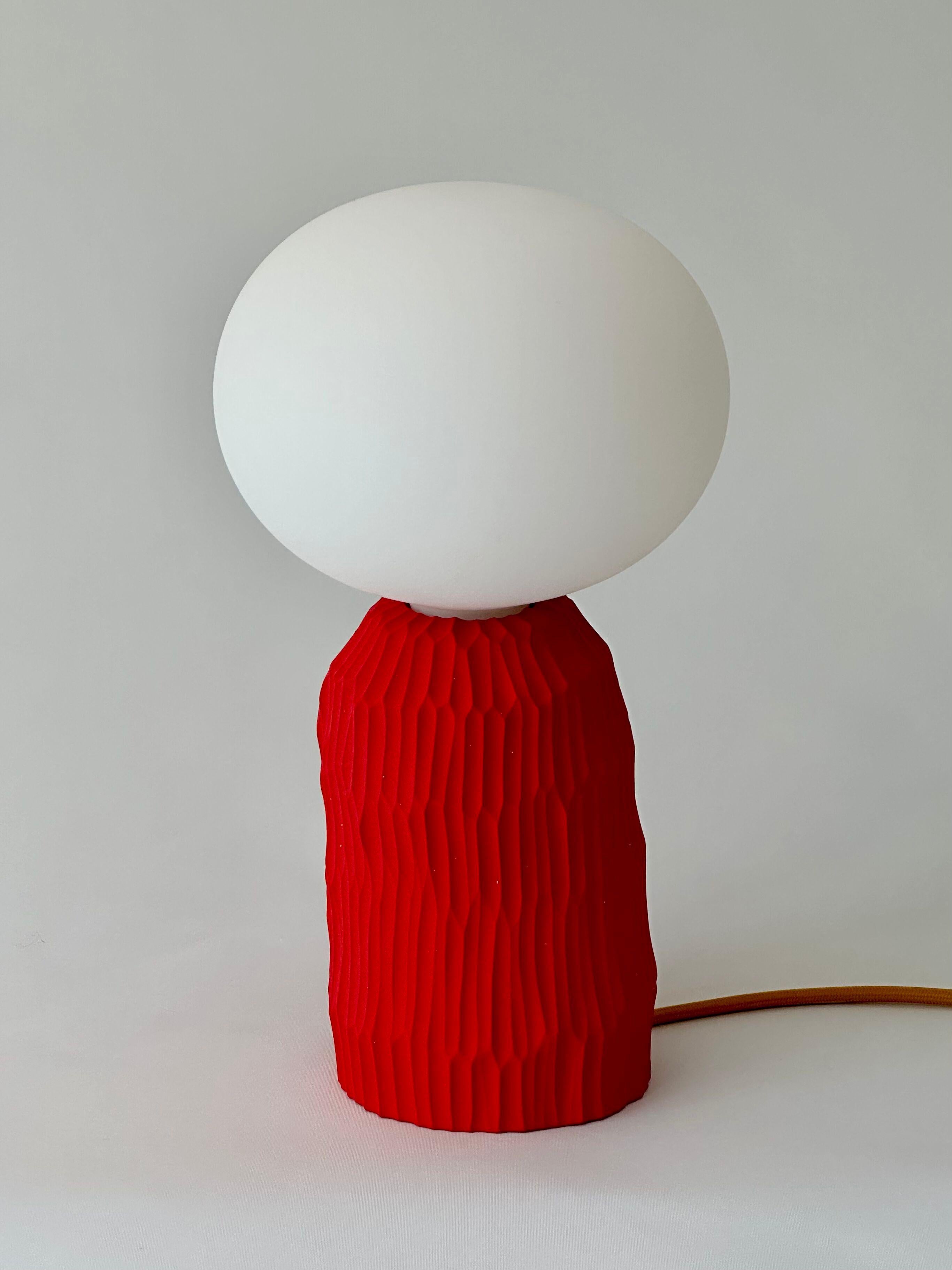 The lamp is a simple and minimalist hand formed ceramic table lamp without a lampshade. Its unique textural base is hand carved in a signature design, with a distinct natural grain from its clay origins. It has been designed to create a unique