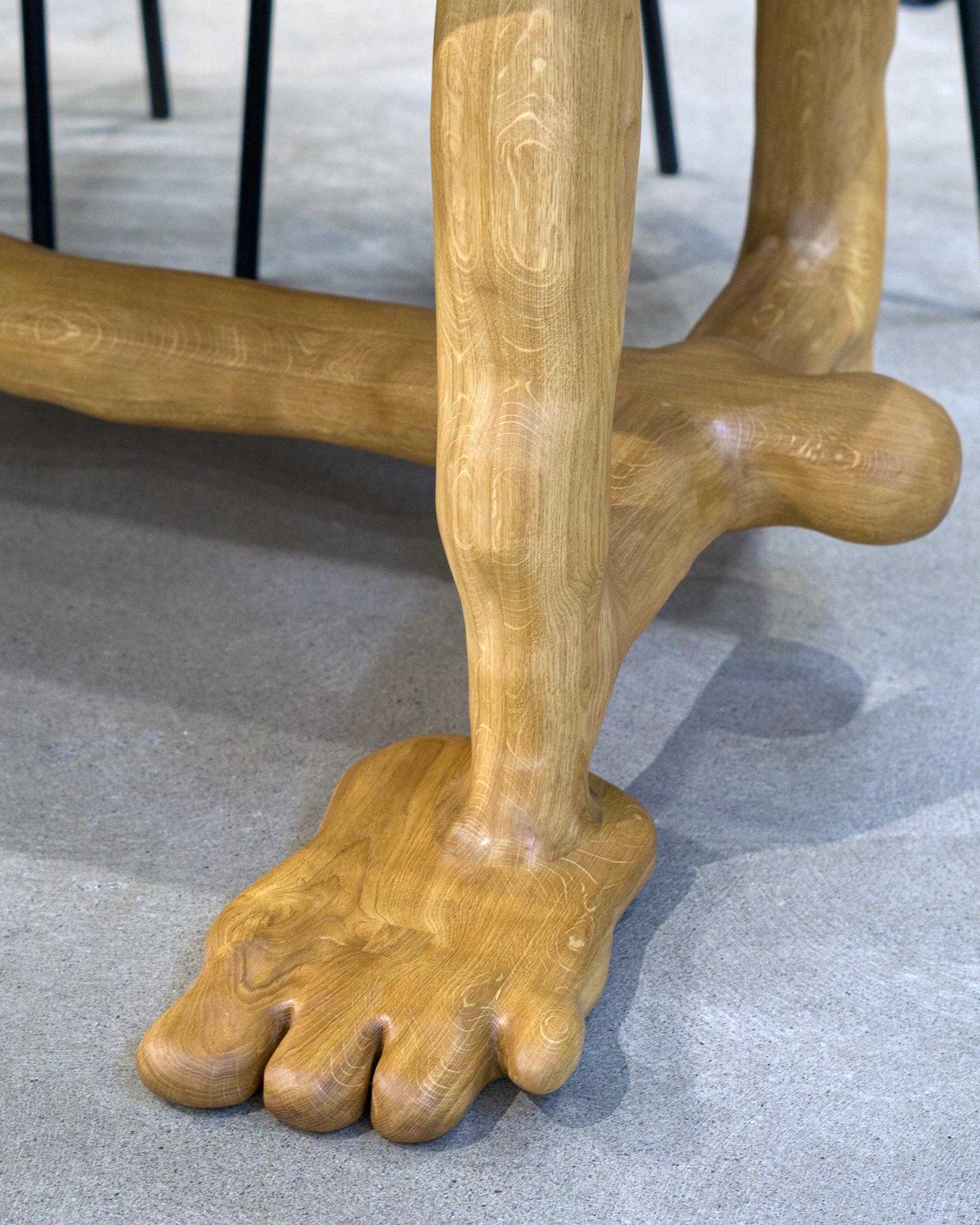 The Leg Dining Table is sculpted using various hand tools, making each piece unique with its own distinctive wood grain. The sculptural table is characterized by its seamless flow, with no sharp edges or corners. It is crafted from a one piece of