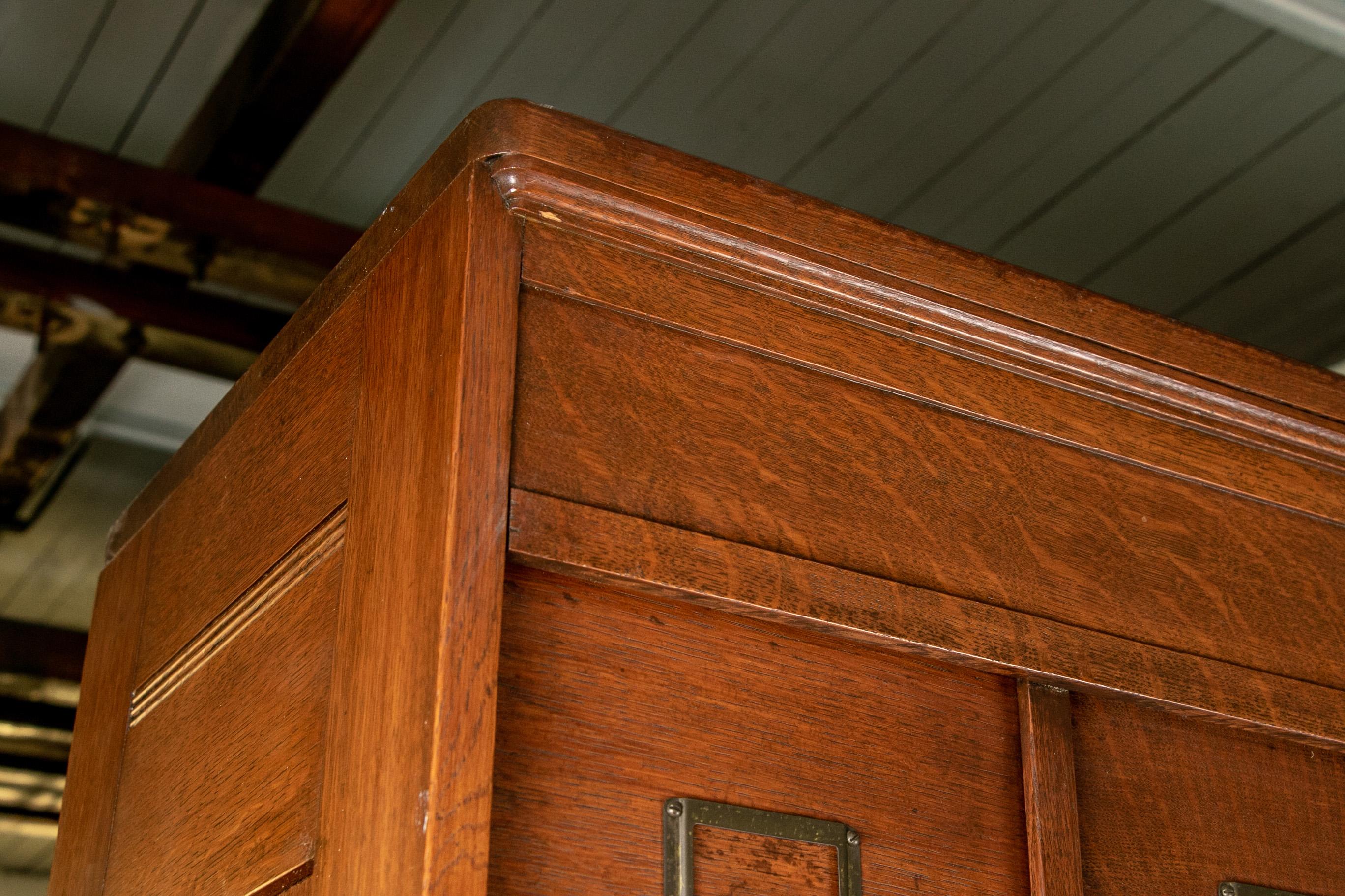 The M. Ohmer’s Sons Co. [Dayton, OH] cabinet file, oak, rectangular form with inset paneled sides, top portion with two vertical rows each with 12 upward sliding doors that open to reveal storage compartments. The lower portion with seven stacked
