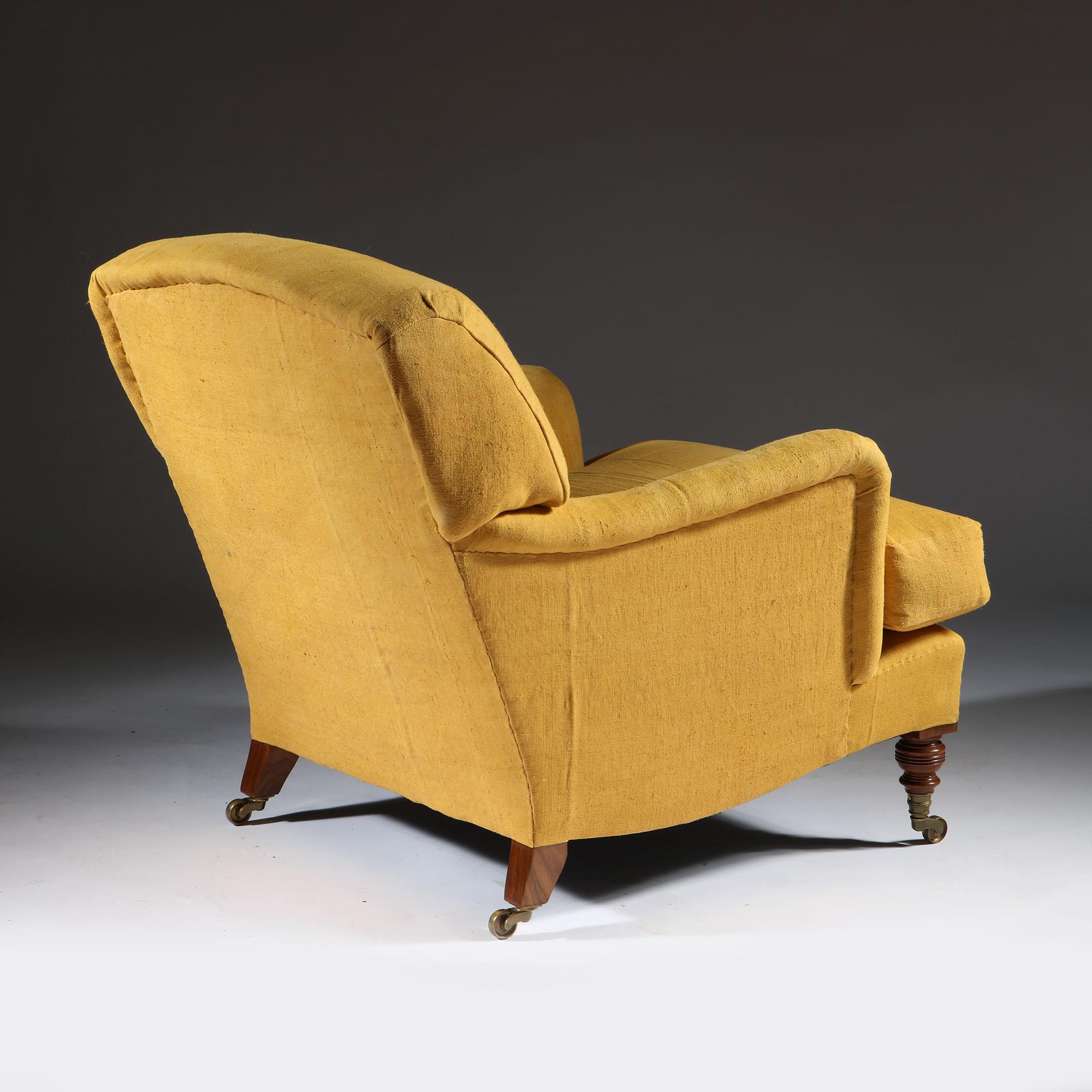 A fine handmade easy armchair, the frame modelled on an original by Howard and Sons, constructed from beechwood, the legs in walnut with brass castors. Upholstered using traditional methods using feather and down. All components made in Britain.