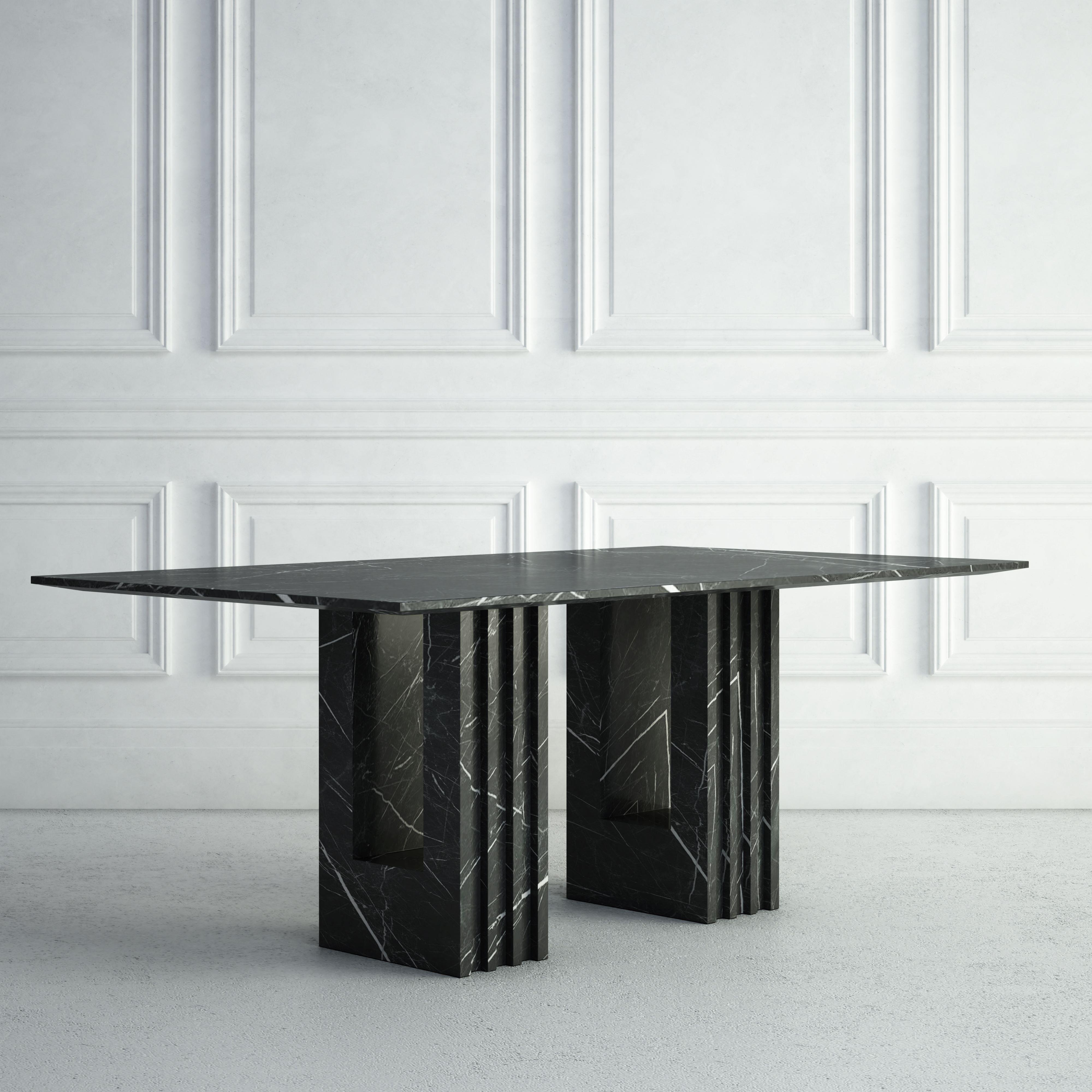 The Madeleine is a sleek modern dining table.  The top is made from an elegant thin rectangular stone slab.  Each of the two legs are also rectangular, but feature fluting on the outward-facing sides, along with a smaller rectangular cut-out through