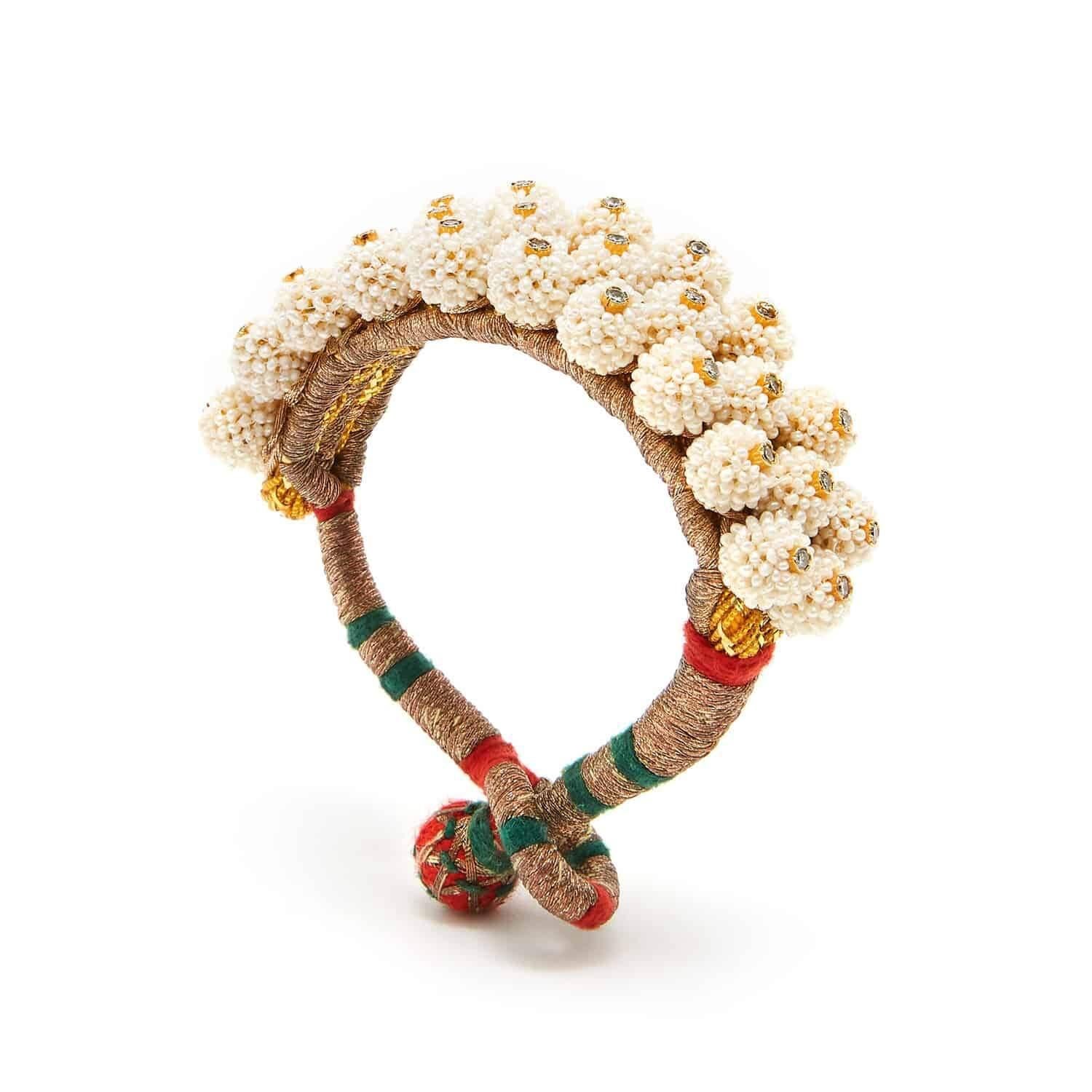 The Maharani Pearl Cuff is inspired by a pair of pearl cuffs owned by the Maharani of Balunda. A hand stitched tightly woven silk cuff studded with tiny pearls highlighted by tiny twinkling white topaz.

- Size 7 with a silk bobble closure

From the