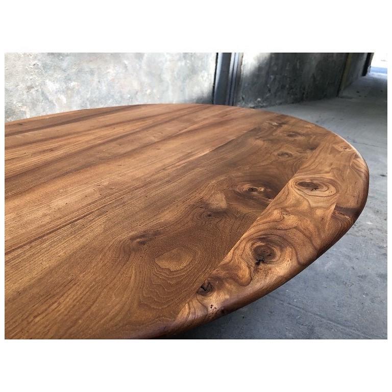 Une table basse de style japonais fabriquée à partir de bois d'orme français récupéré. Le beau grain noble est accentué par les tons chauds que fait ressortir l'application d'une cire dure mate. Le plateau ovale permet de se déplacer librement
